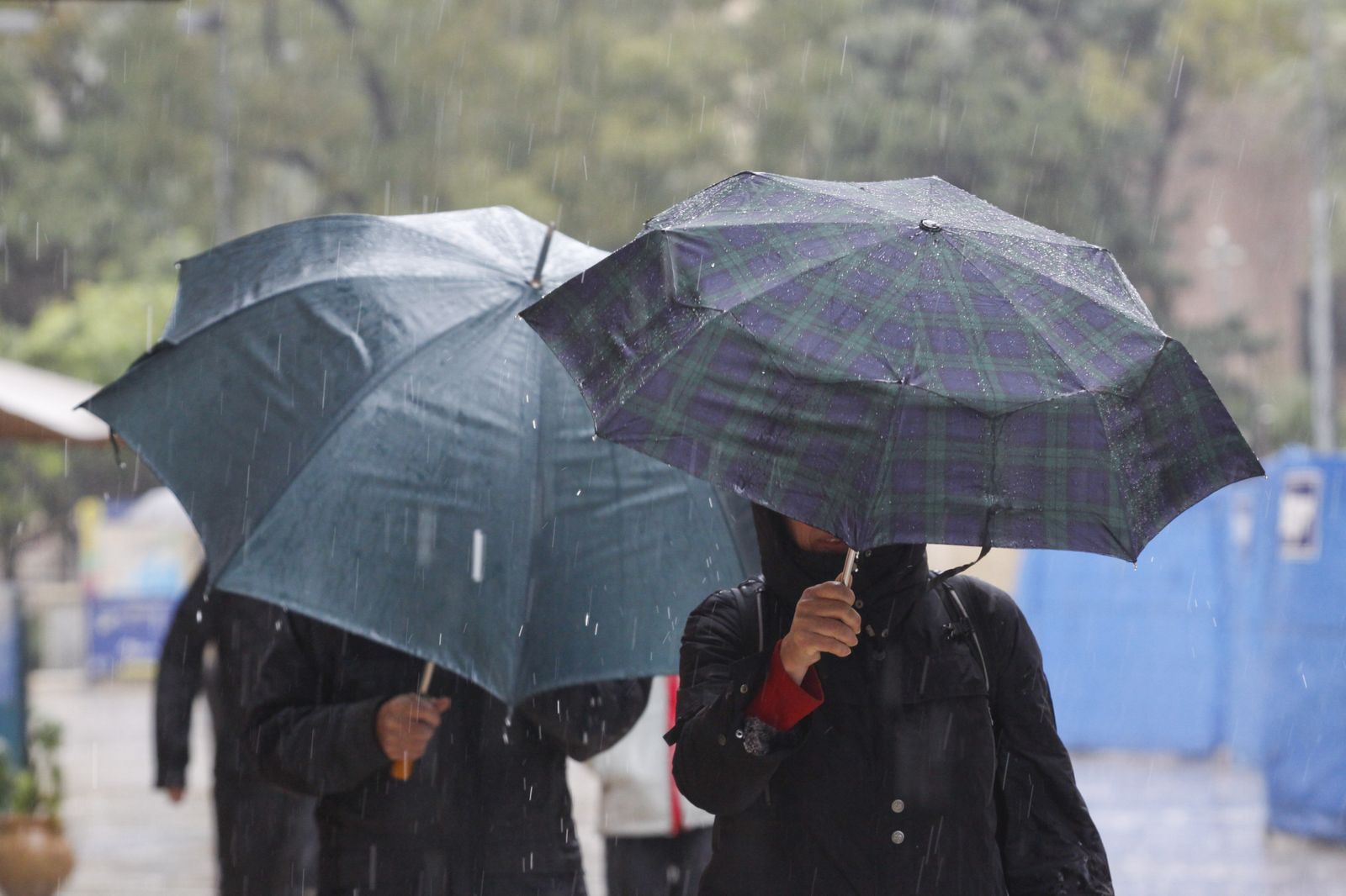 Dos personas pasean bajo la lluvia protegidos con un paraguas.