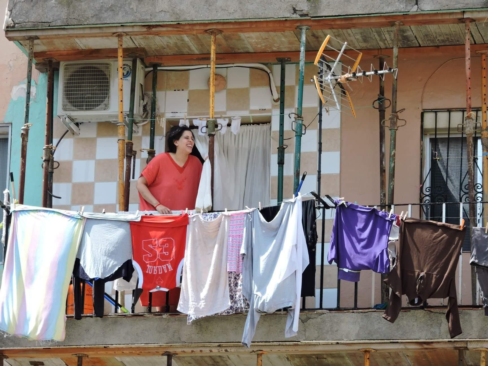 Una mujer tiende la ropa entre los puntales del edificio El Patio