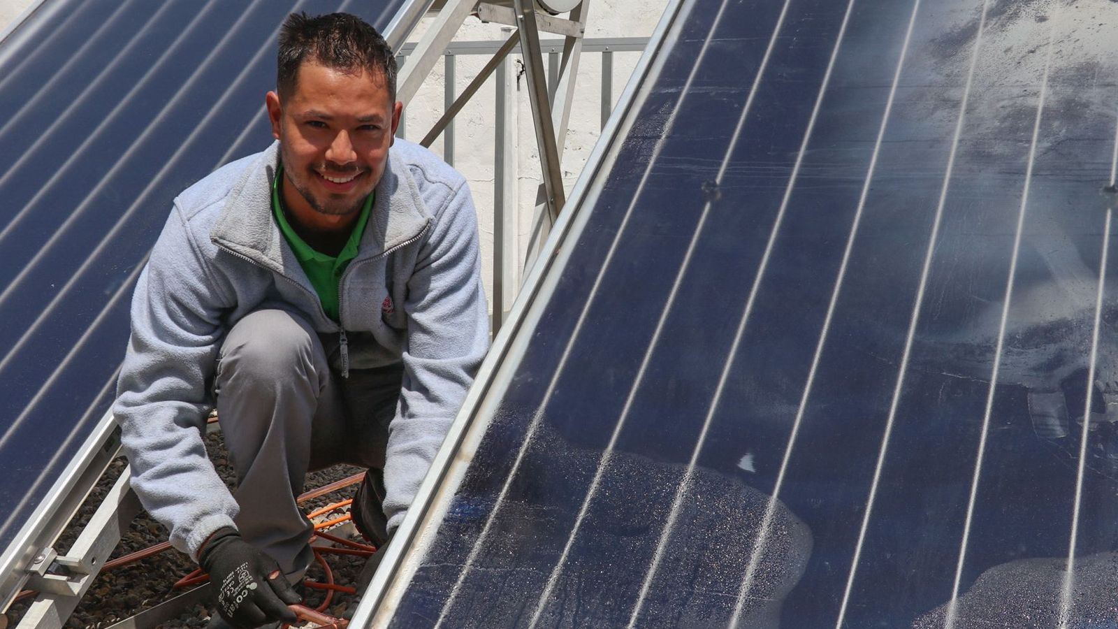 Ronald Medina junto a unas placas solares durante el taller de renovables.