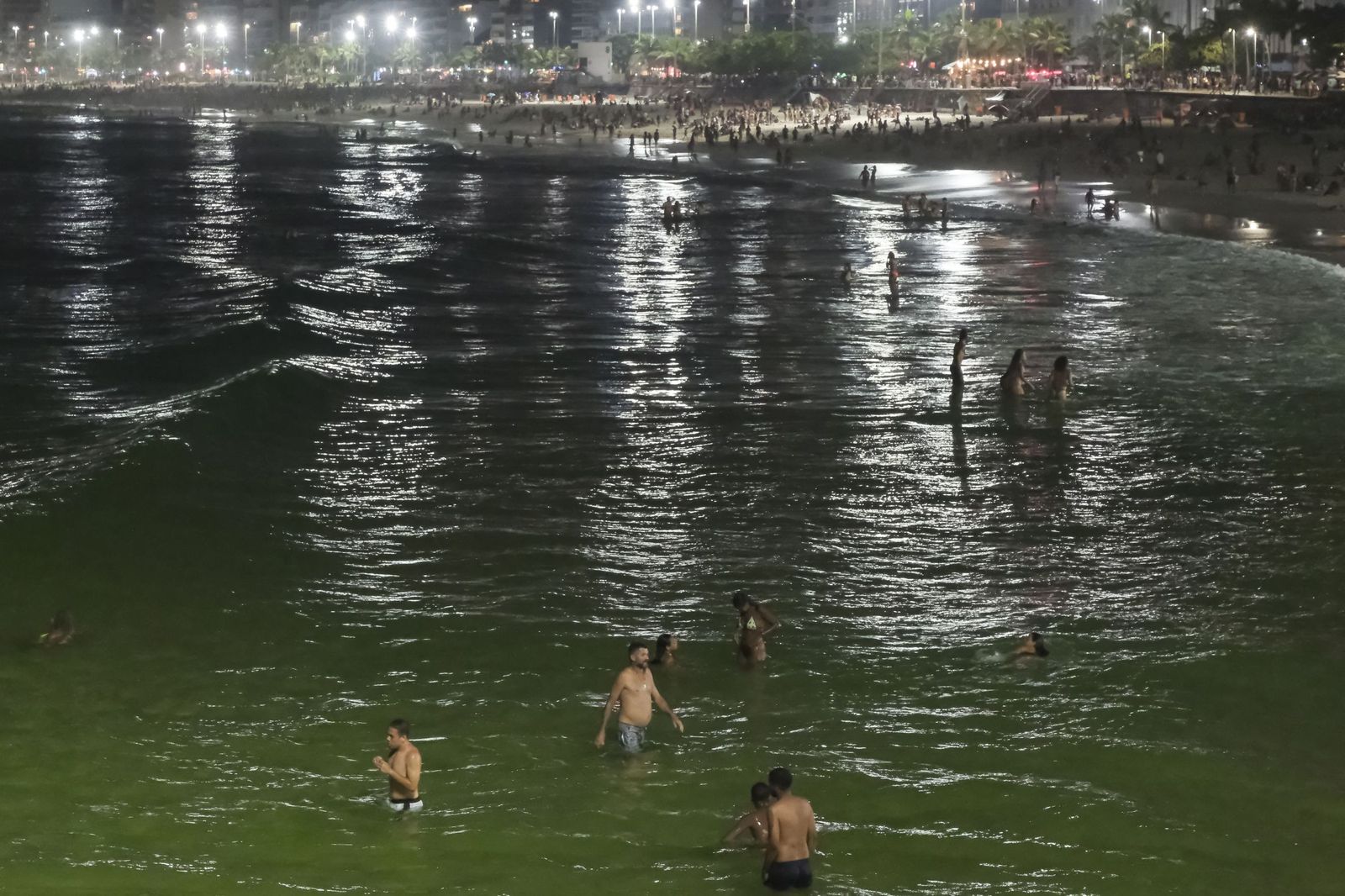 Personas se bañan de noche en el mar de la playa de Arpoador en Río de Janeiro (Brasil).