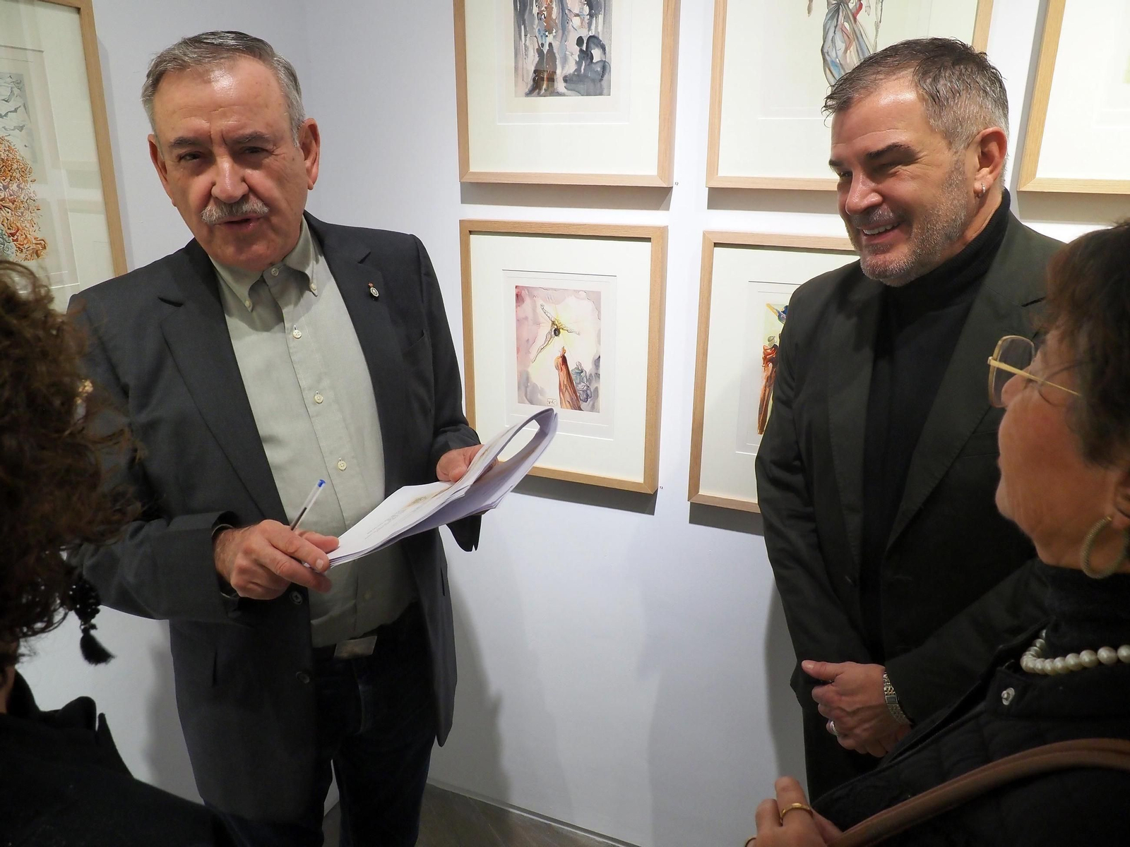 Los galeristas John Holland (d) y Enrique Santana hablan con algunos de los asistentes a la inauguración