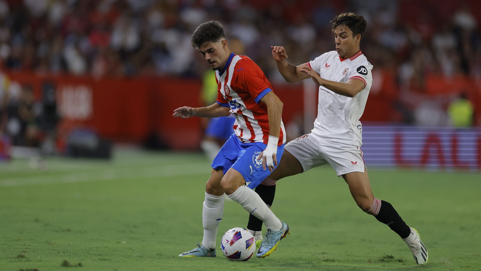 Óliver Torres trata de robarle un balón a Miguel Gutiérrez.