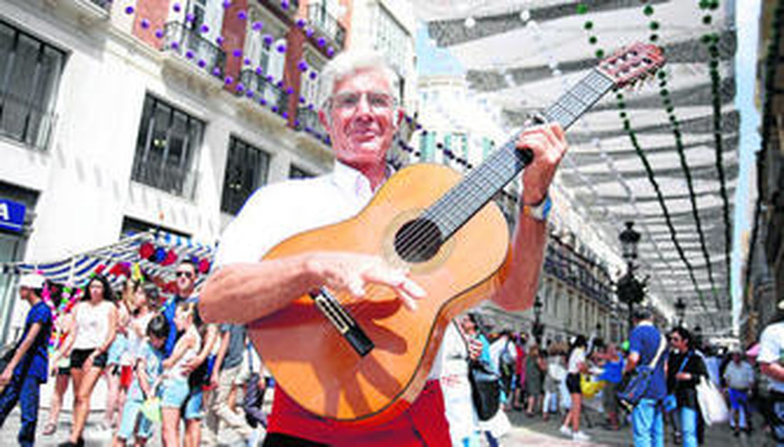El artista malagueño posa con su guitarra frente a la calle Larios, el epicentro de la Feria de Málaga.