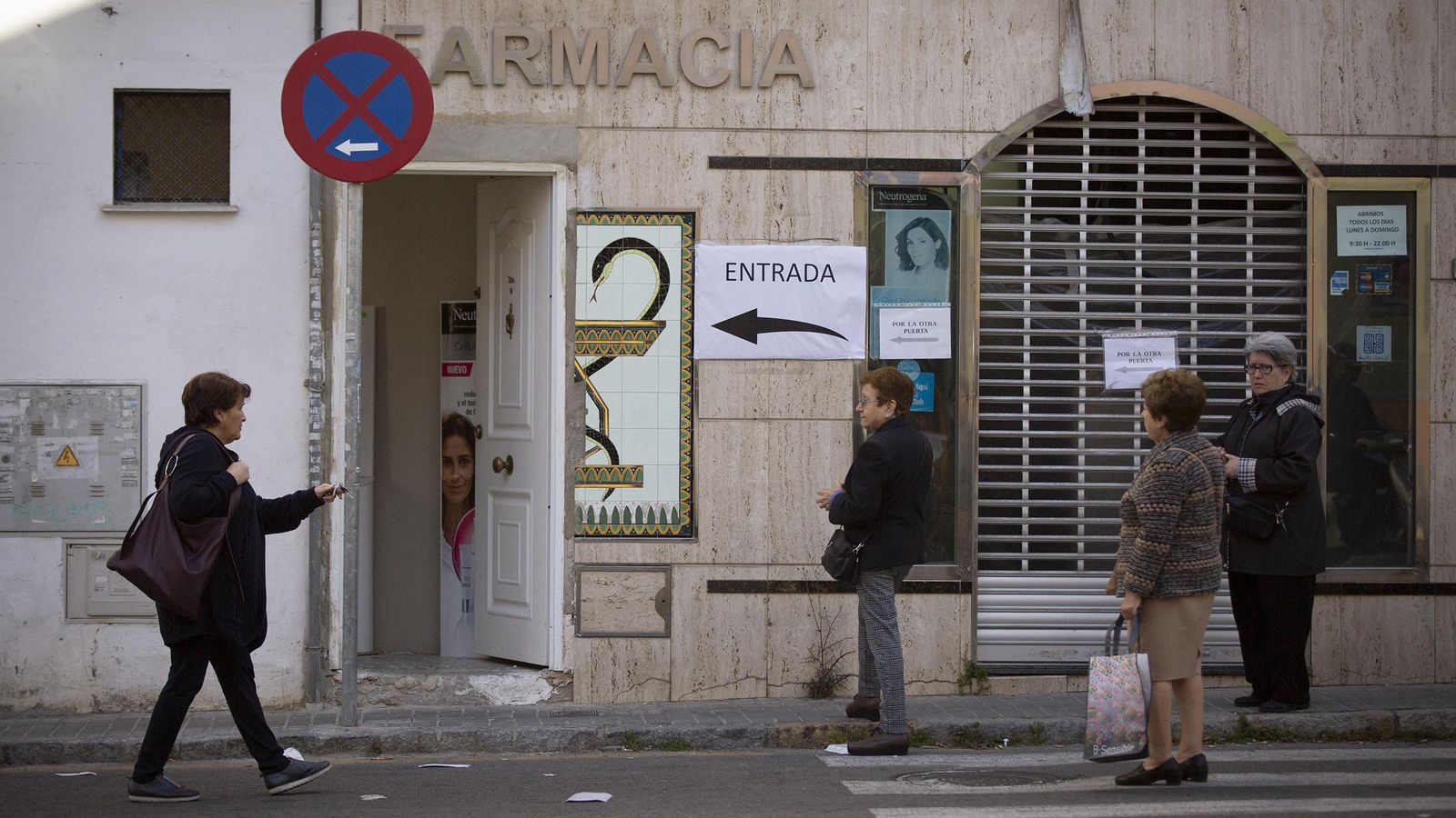 Colas la puerta de una farmacia en la que han cerrado su acceso principal.
