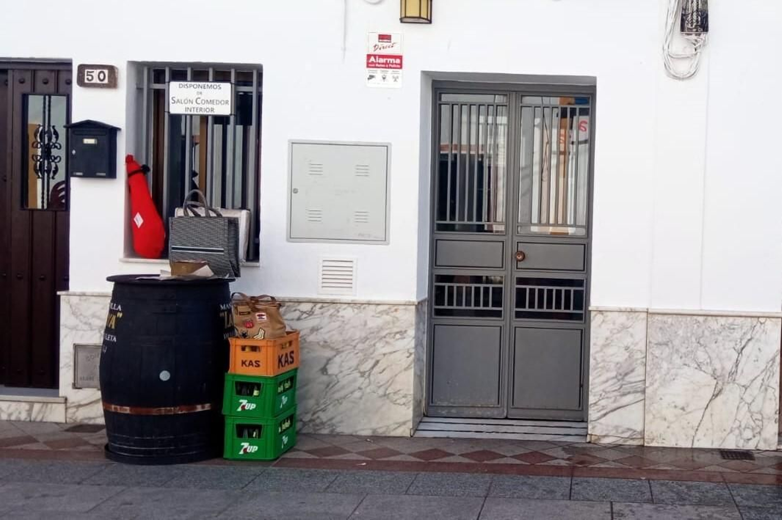 La fachada del bar que ha tenido que cerrar y los productos que se están rifando.