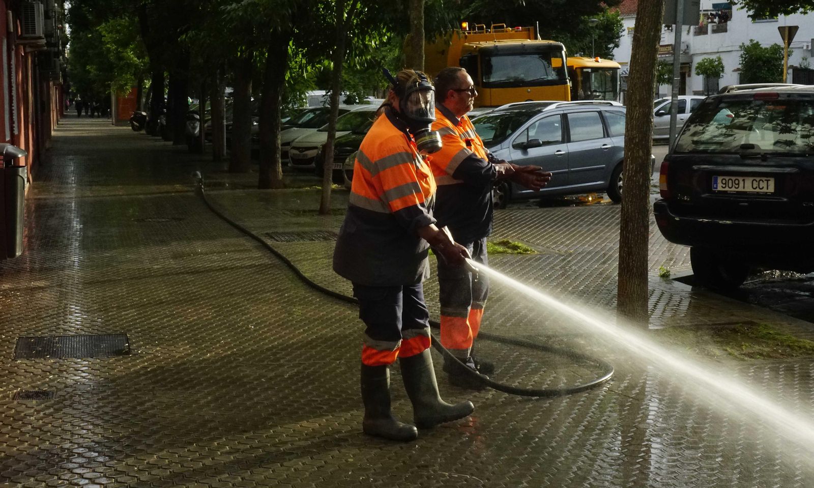 Dos trabajadores de Lipasam en el baldeo de una calle.