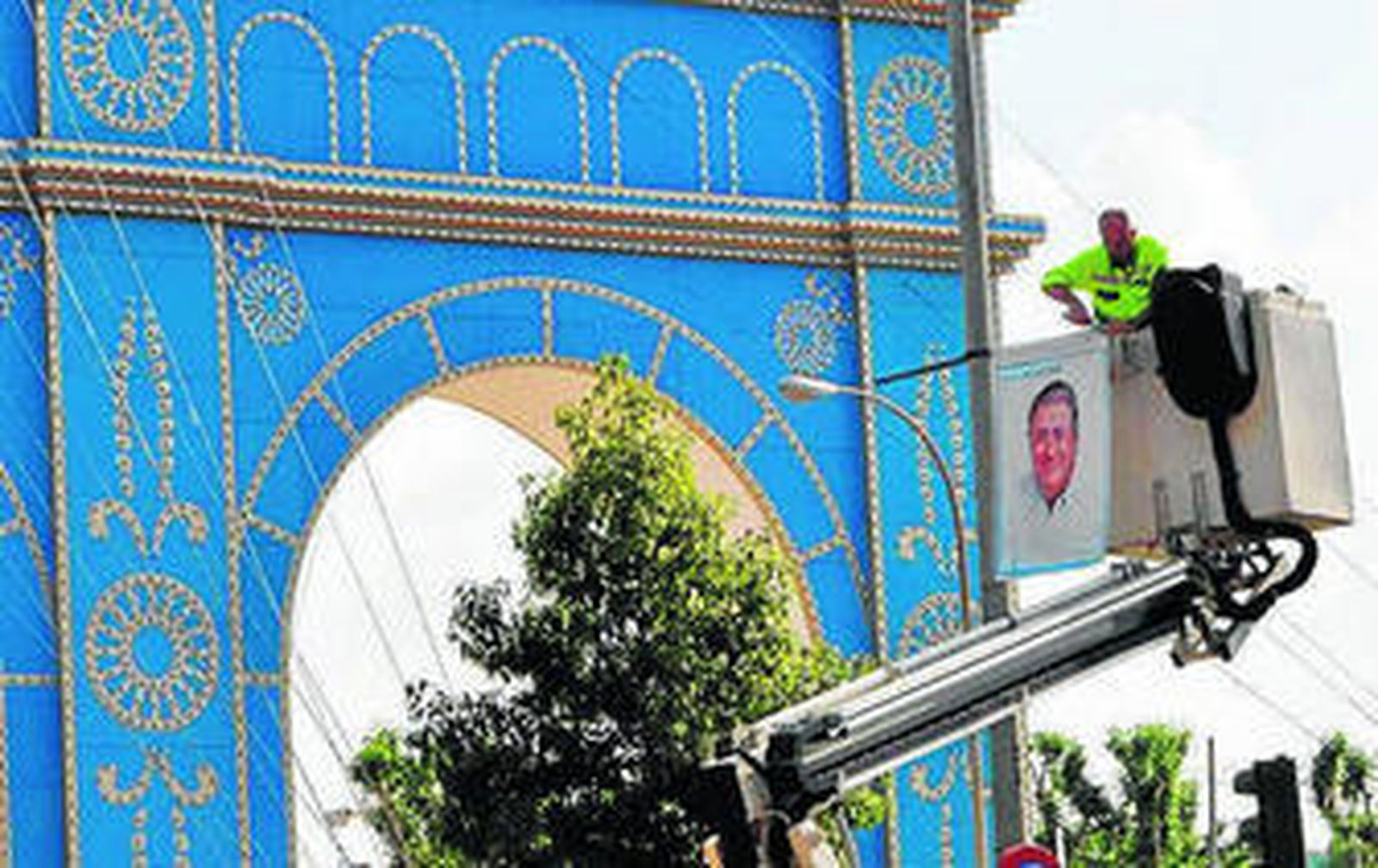 Un operario retira carteles de Zoido ante la portada de Feria.