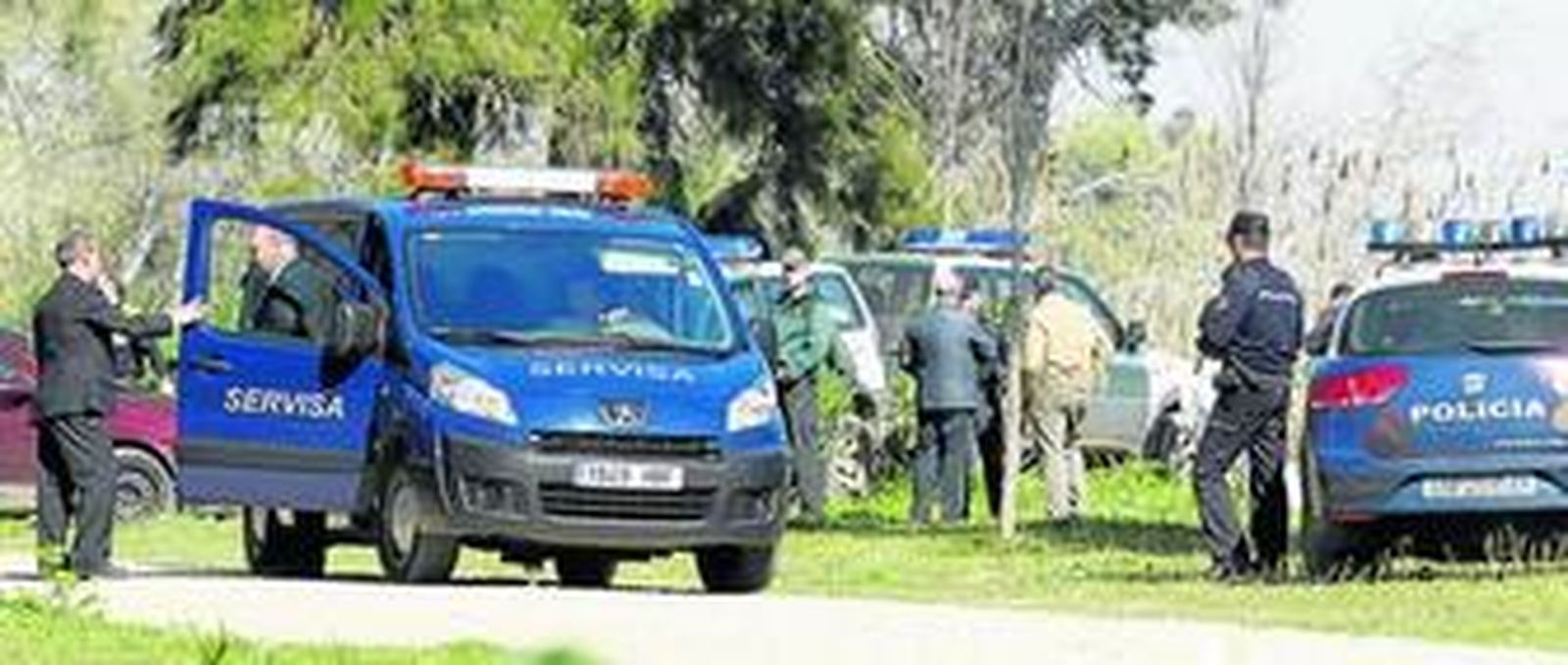 Policías, guardias civiles y trabajadores de los servicios funerarios, en la orilla próxima al lugar donde apareció el cuerpo de María Isabel Sierra.