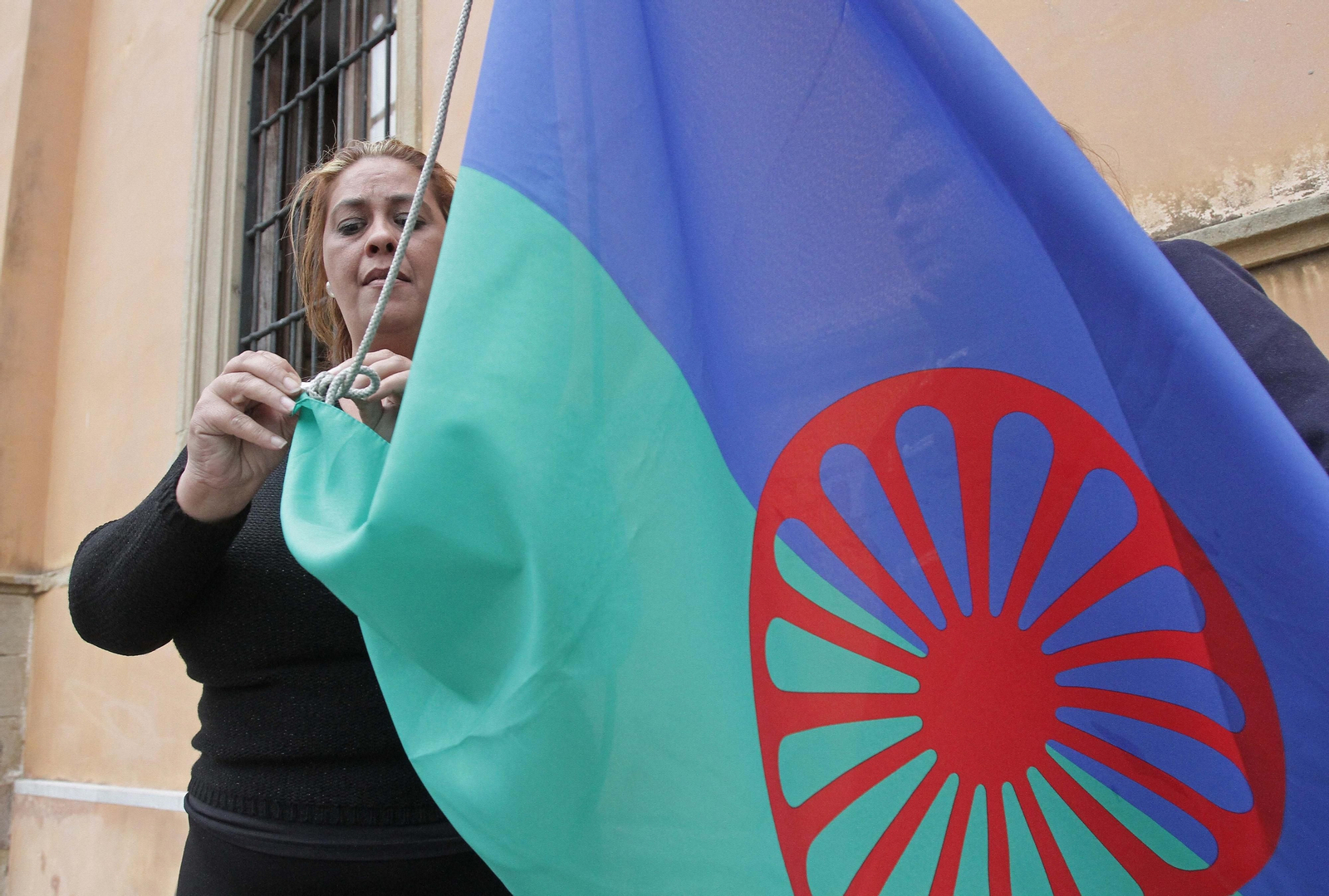 Mujer alzando la bandera del pueblo gitano.