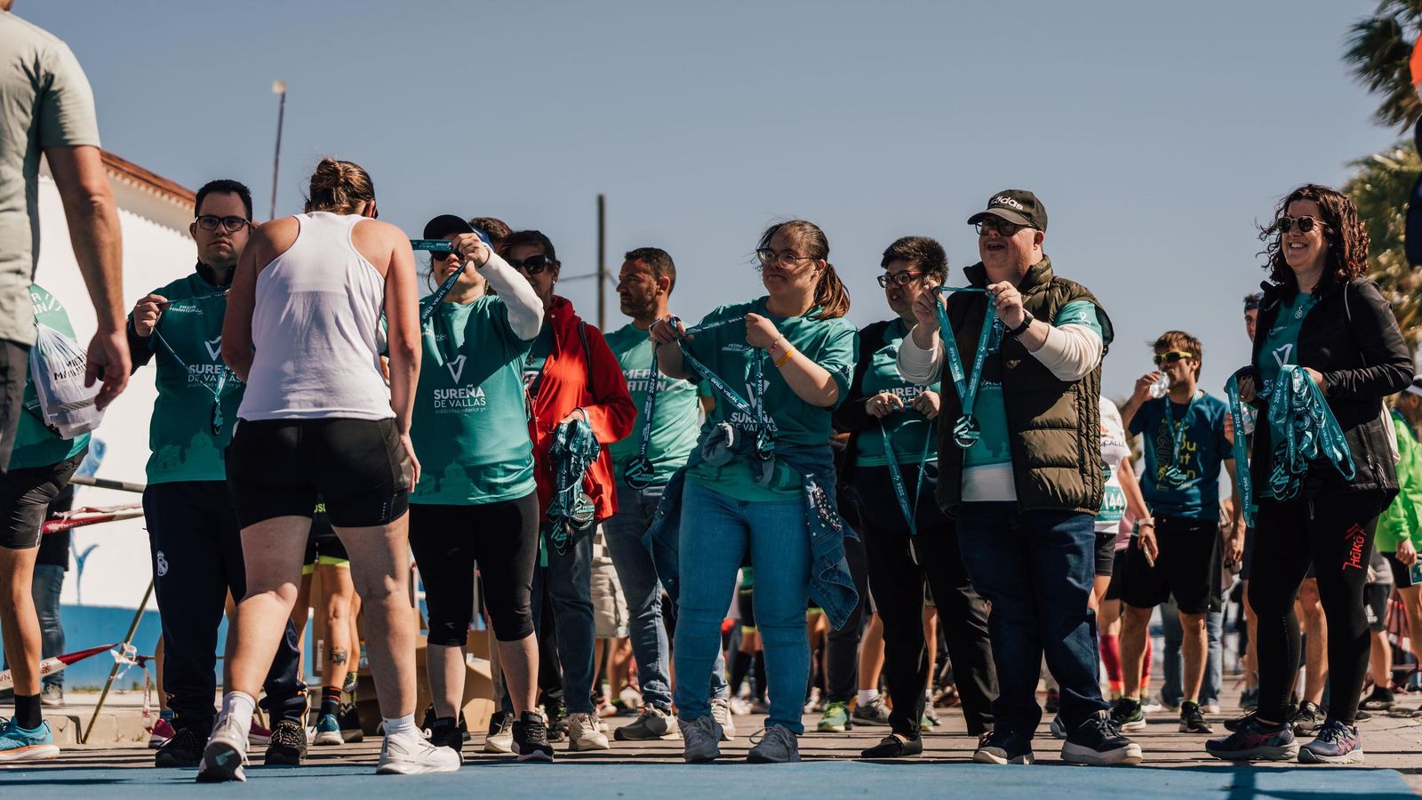 ‘Voluntarios entregan medallas a los participantes en esta prueba.