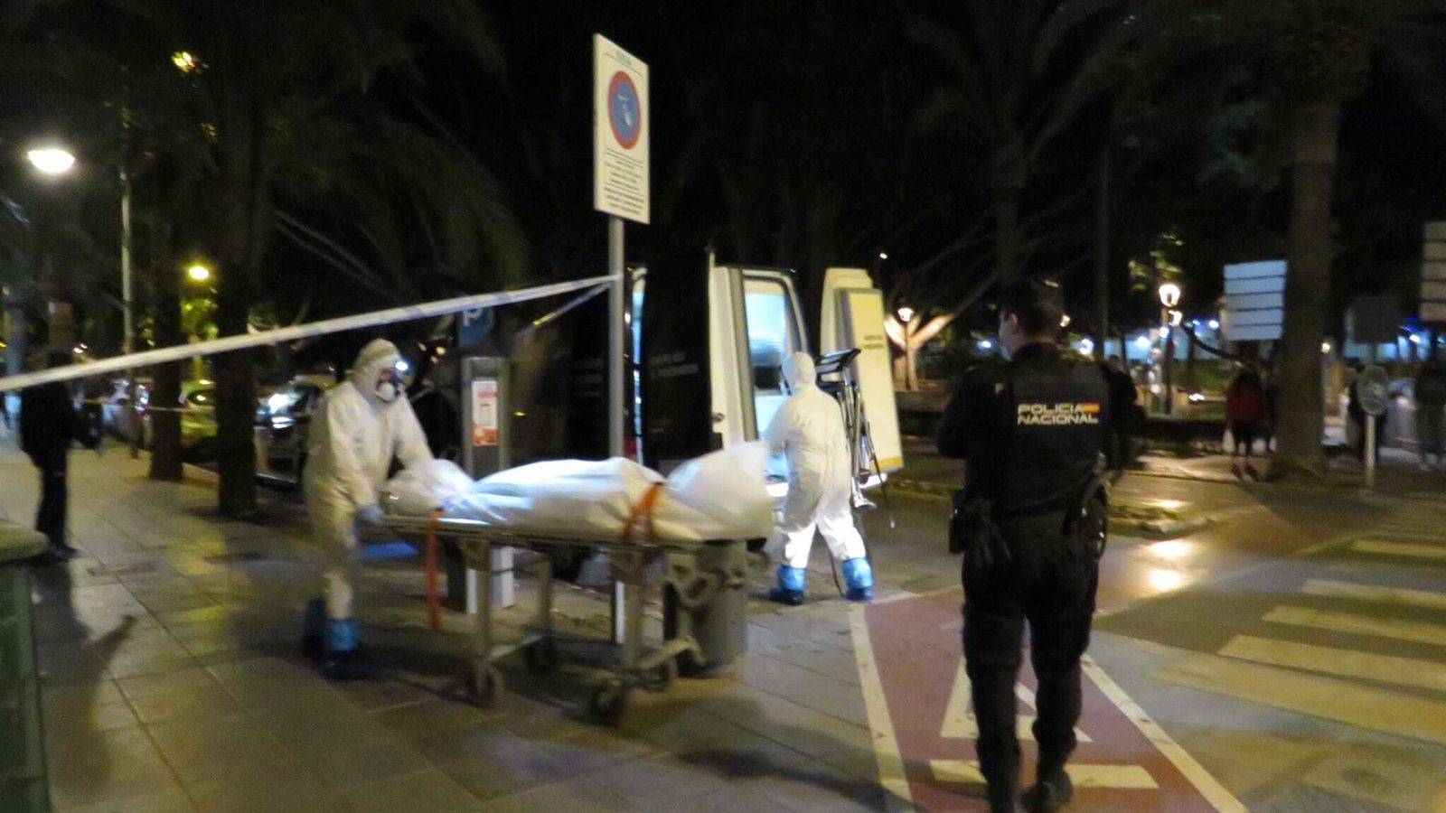 Agentes conducen el cadáver hacia el vehículo funerario.