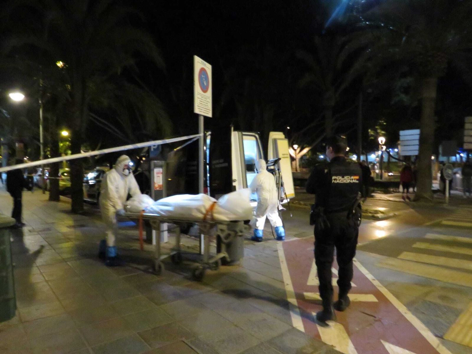 Agentes conducen el cadáver hacia el vehículo funerario.
