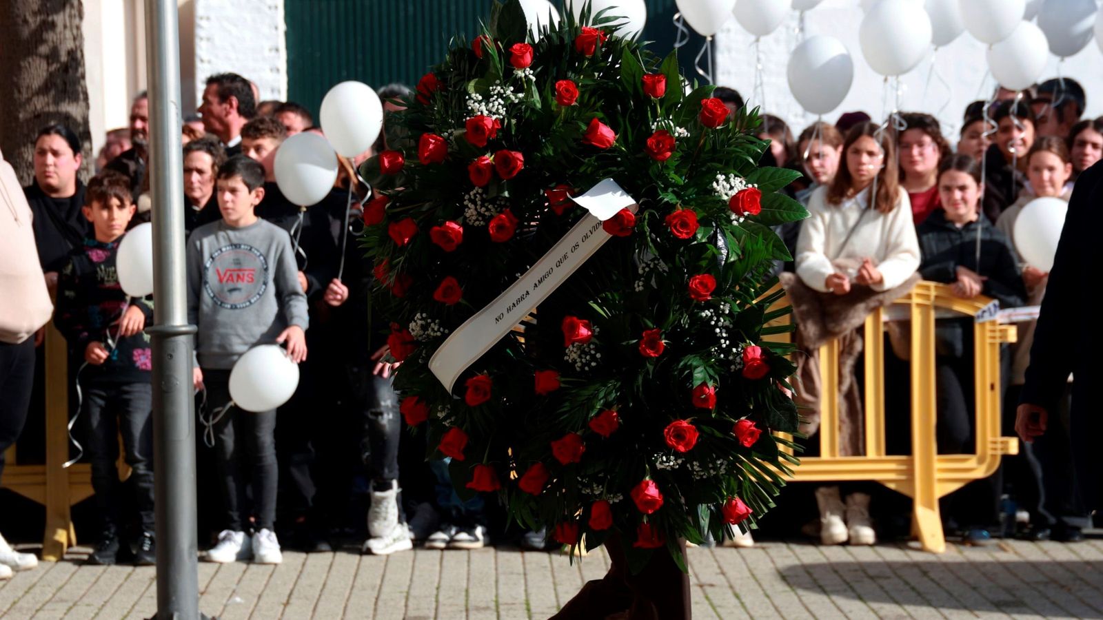 Una persoan lleva una de las coronas de flores para los fallecidos en la tragedia ferroviaria.