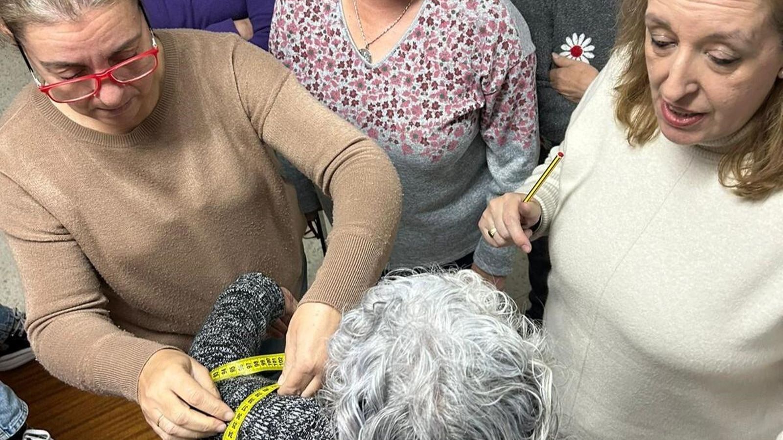 Las mujeres toman medidas a una compañera.