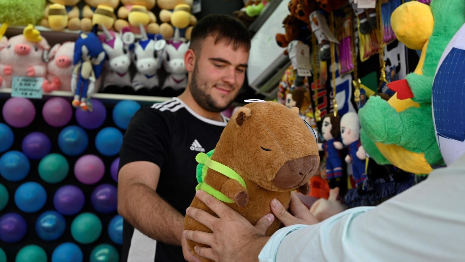 Un feriante entrega un peluche de capibara en la Feria de Córdoba. Un feriante entrega un peluche de capibara en la Feria de Córdoba.
