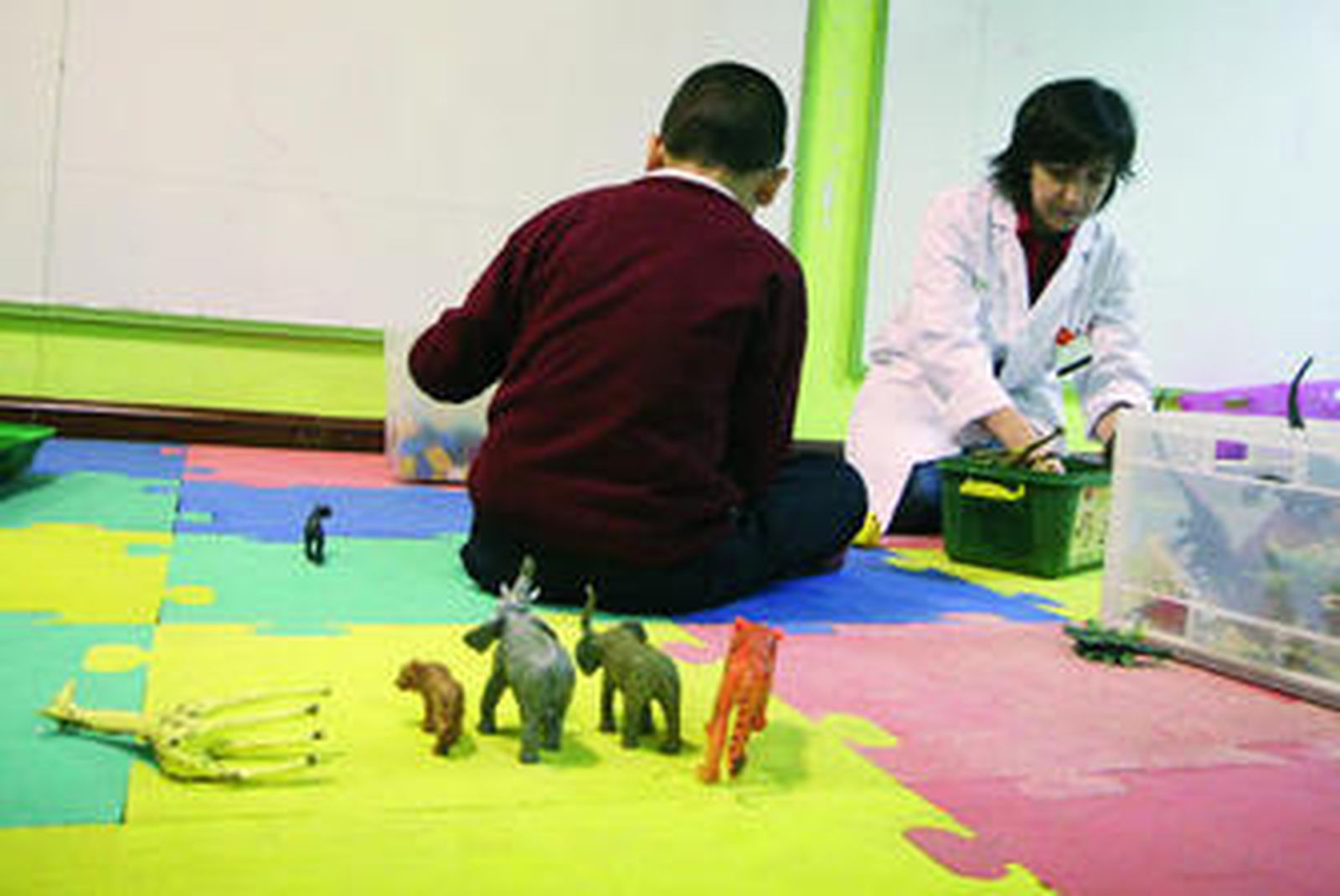 Una trabajadora del hospital de día del área de Salud Mental del Materno, con uno de los niños en tratamiento.