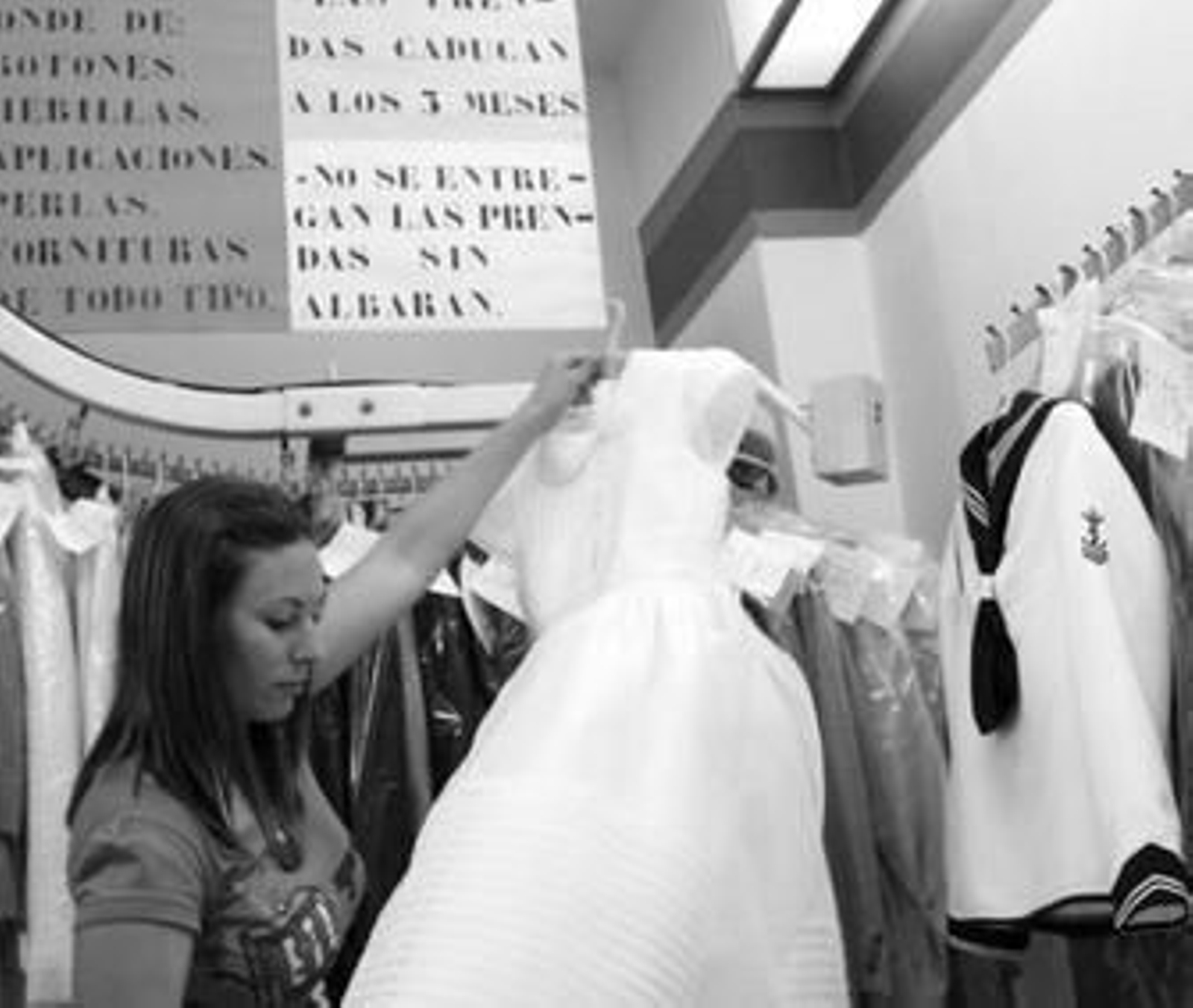 Una dependienta de una tintorería del centro de Algeciras da los últimos retoques a un vestido de primera comunión.