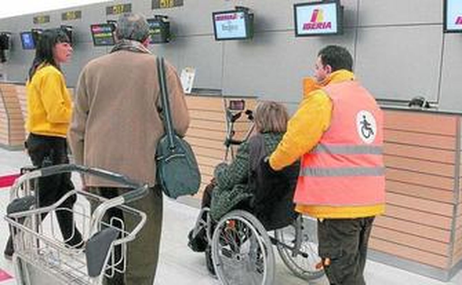 Operarios del Aeropuerto de Almería ayudan al desplazamiento por las instalaciones de una persona de avanzada edad y movilidad reducida.