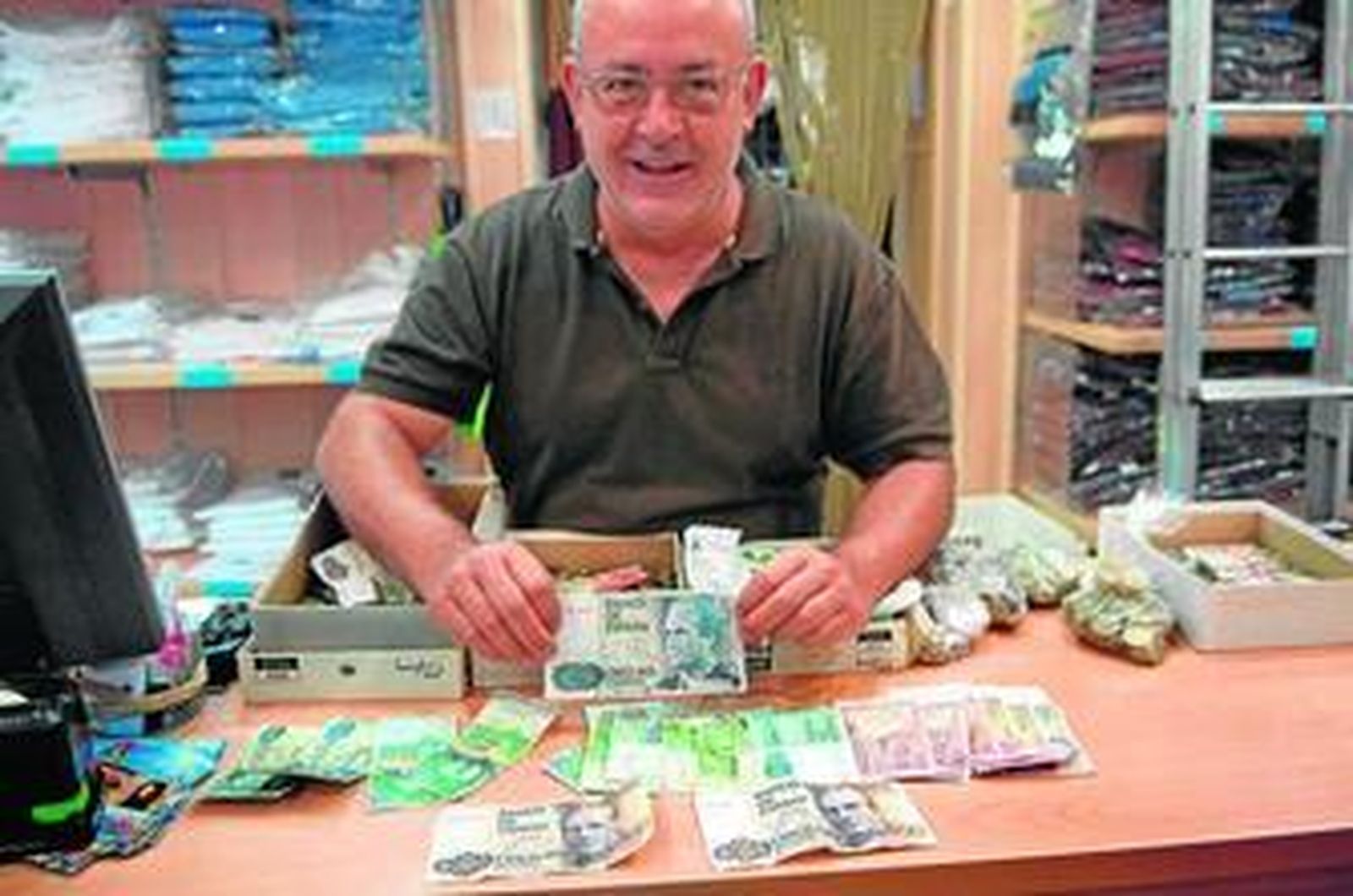 Uno de los comerciantes del centro muestra la gran cantidad de billetes antiguos con los que le han pagado.