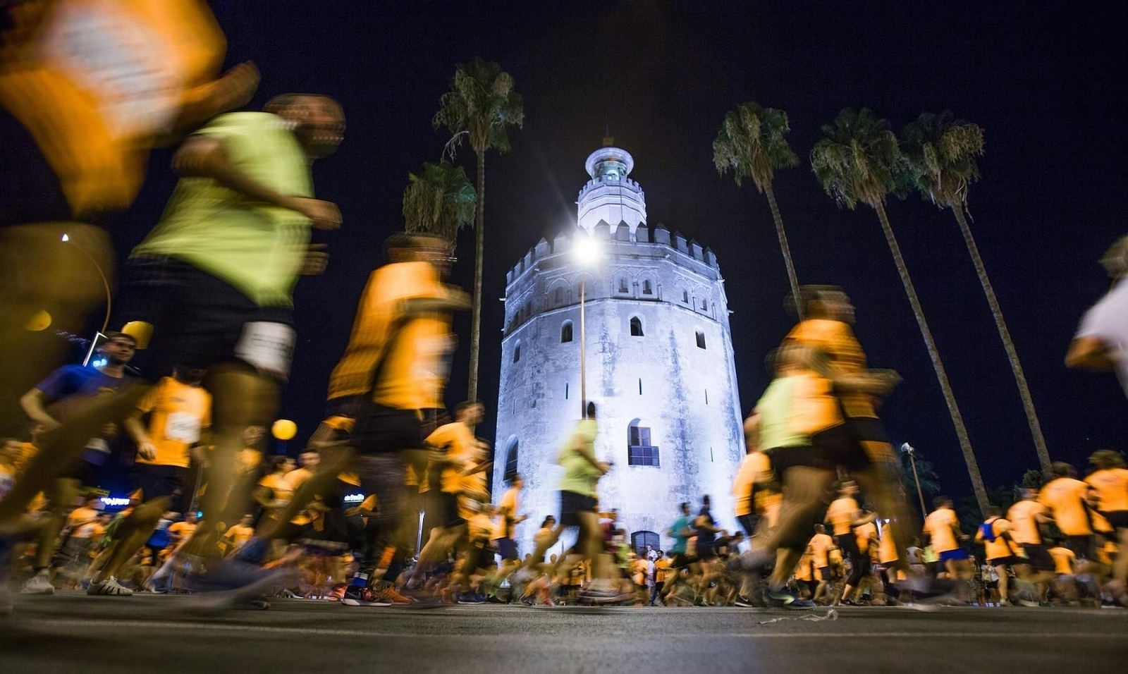 Participantes de la carrera nocturna a su paso por la Torre del Oro