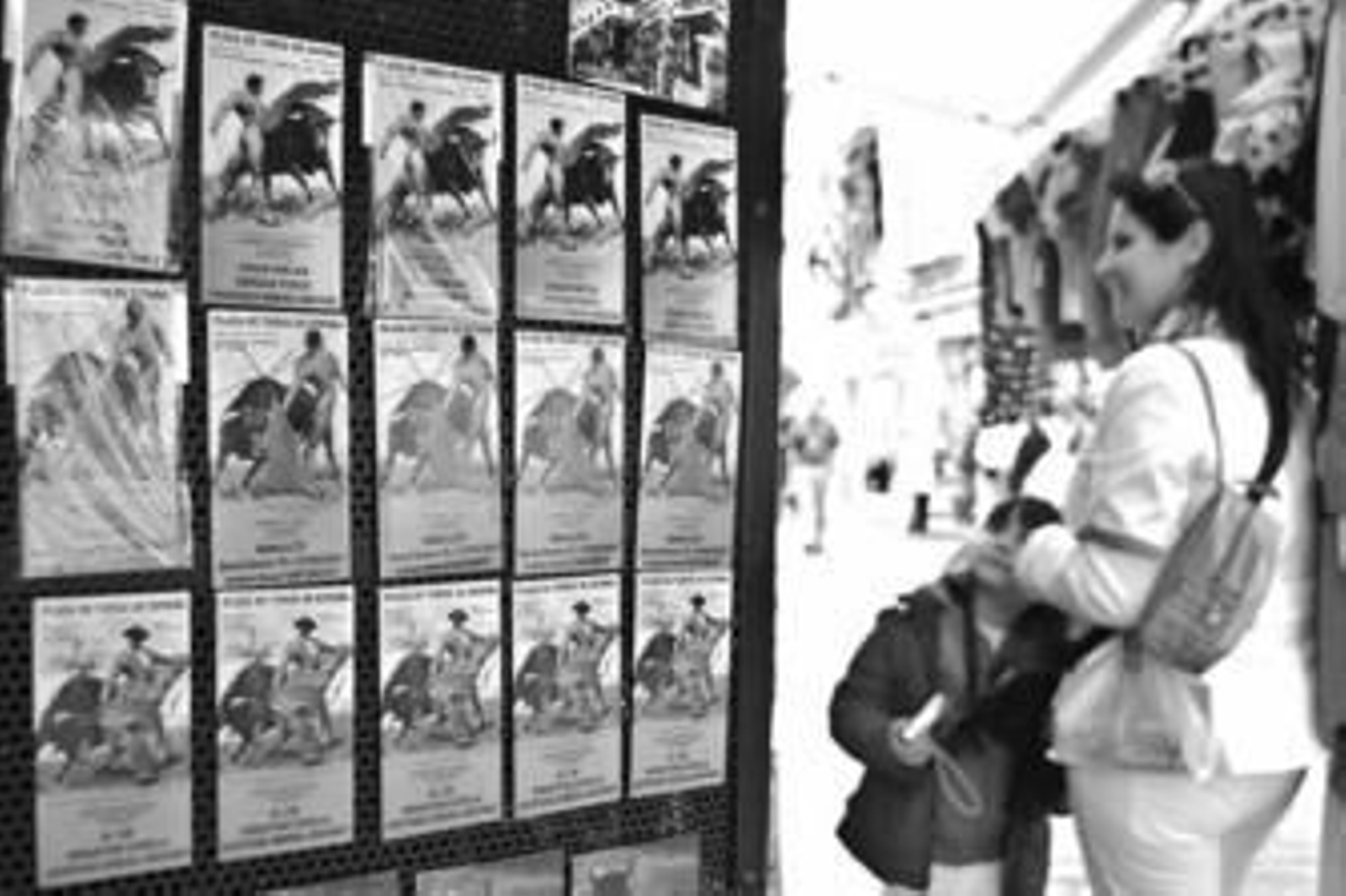 Una turista observa algunos carteles de corridas de toros.