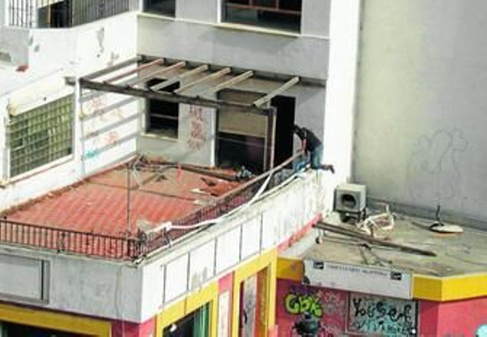 Un hombre accede a una terraza del edificio Escalinata, ayer, saltando desde la terraza del antiguo Cohiba.