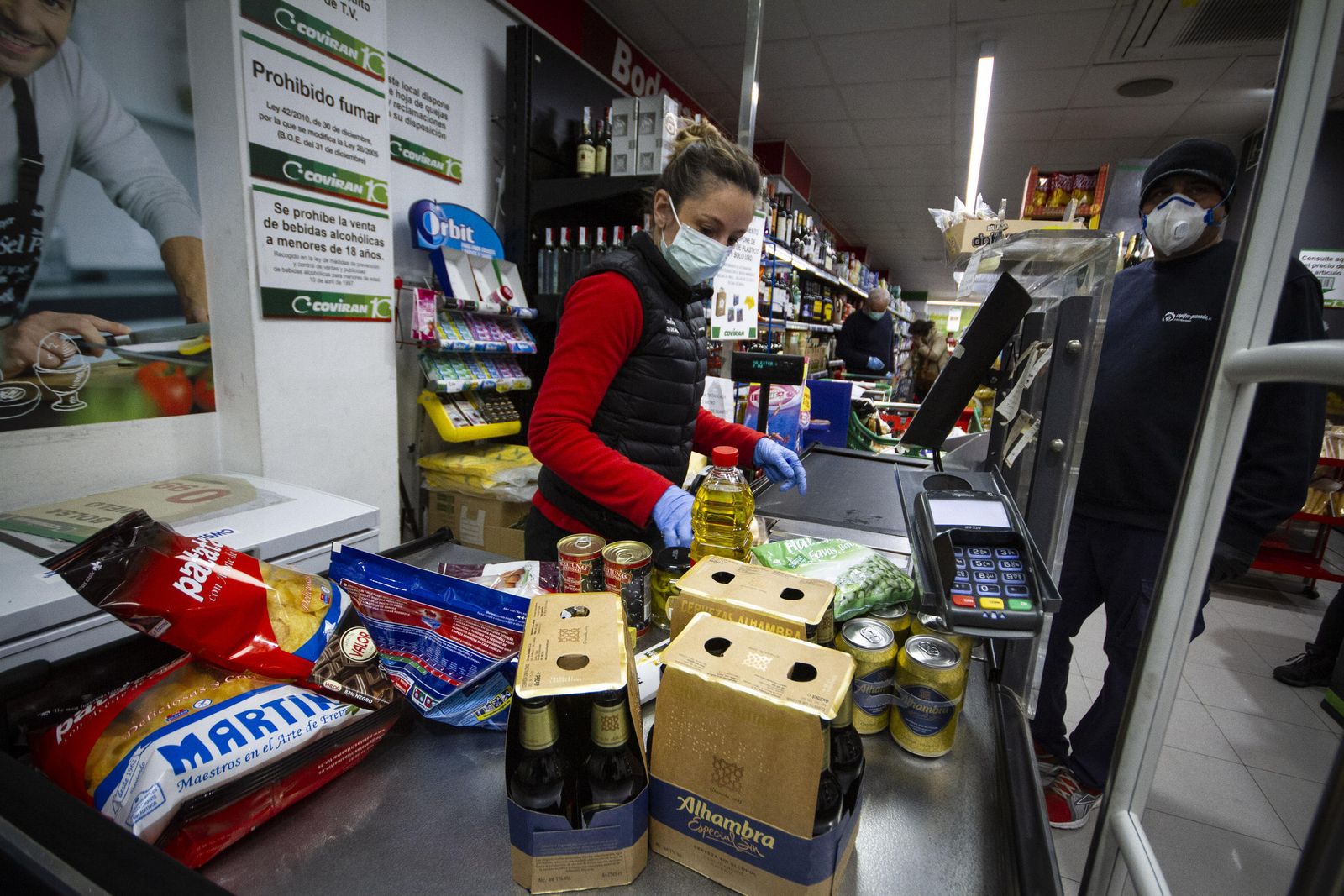Una cajera del Covirán cobra una compra en la que hay snacks y productos de marcas granadinas.
