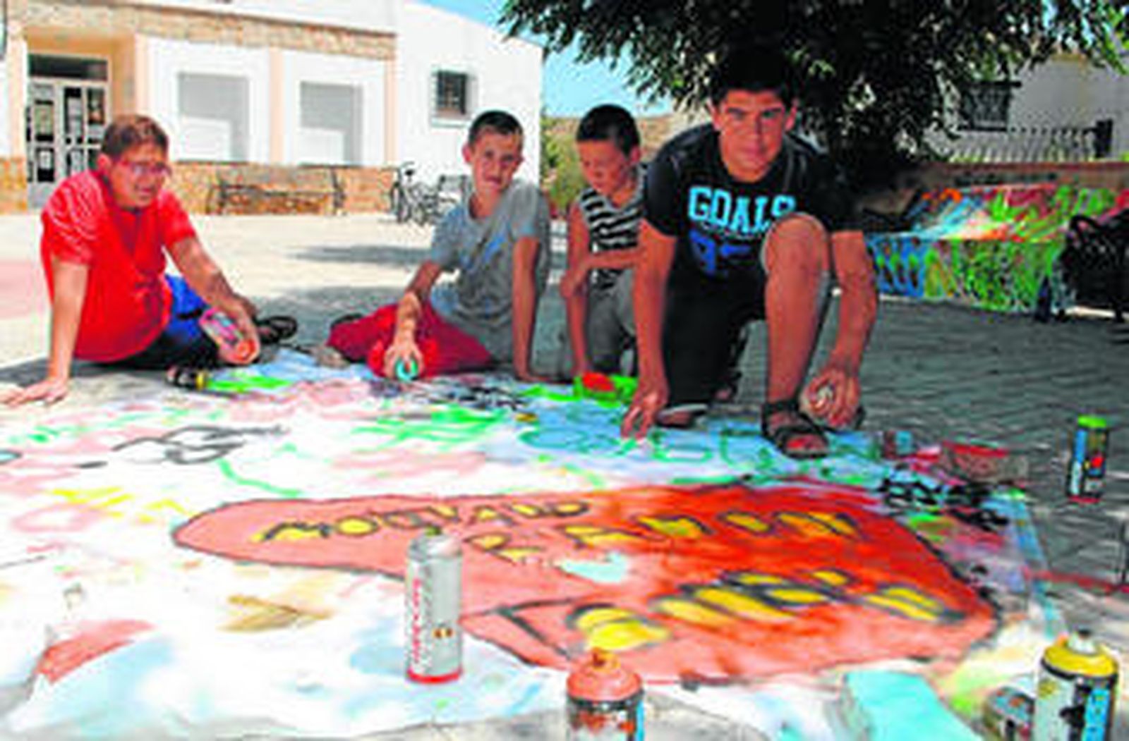 Los más pequeños posan junto al grafiti que realizaban bajo la dirección de Eva Sans, del taller en Hijate.