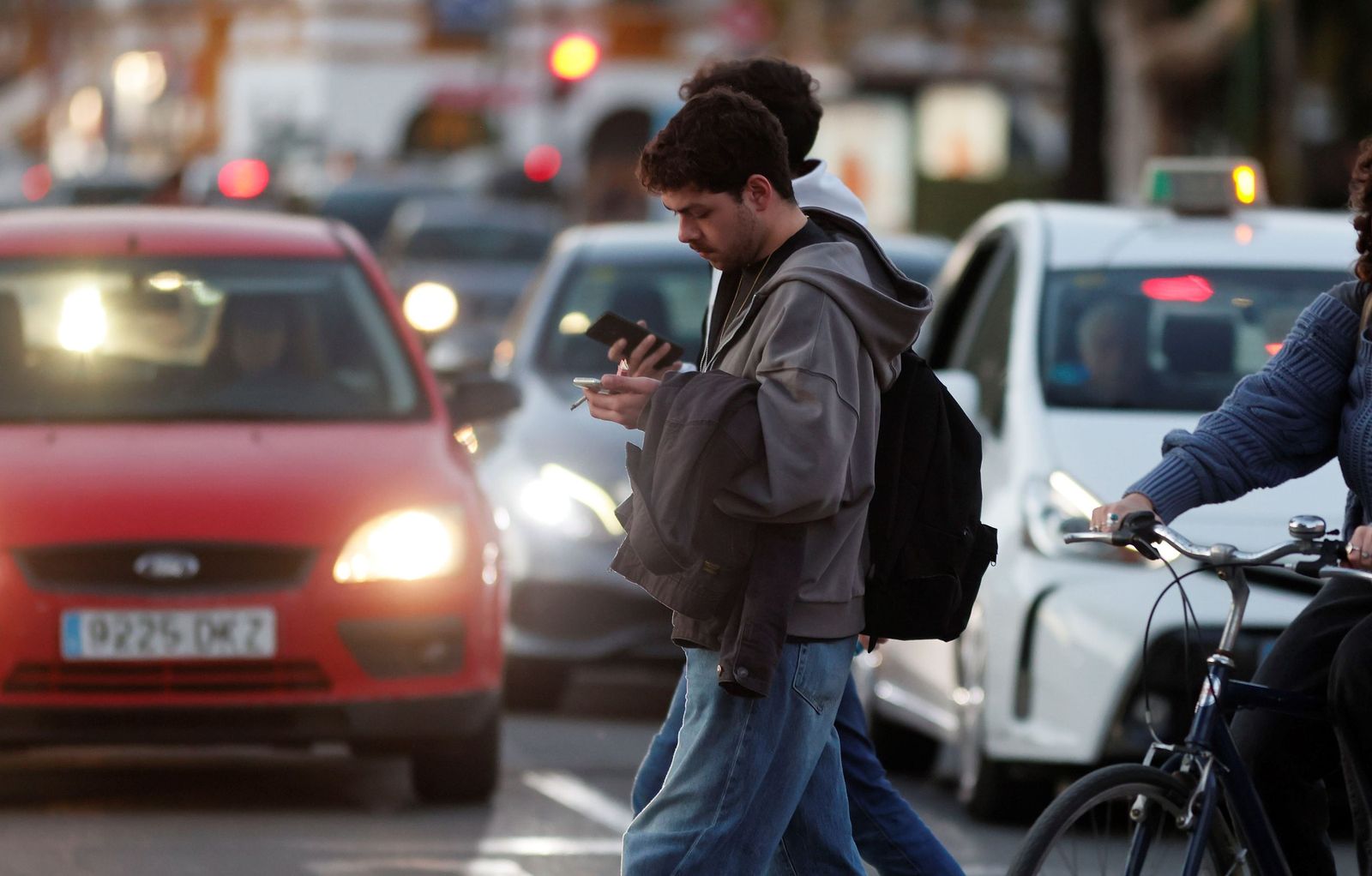 Dos personas cruzan un  paso de peatones mientras miran el móvil, esta semana en Sevilla.