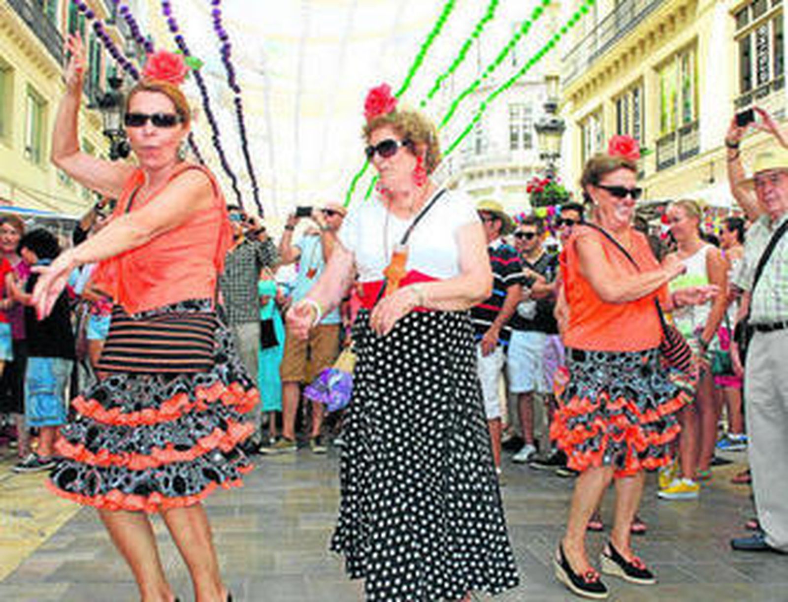 Mujeres disfrutando de la música de una charanga en la calle Larios.