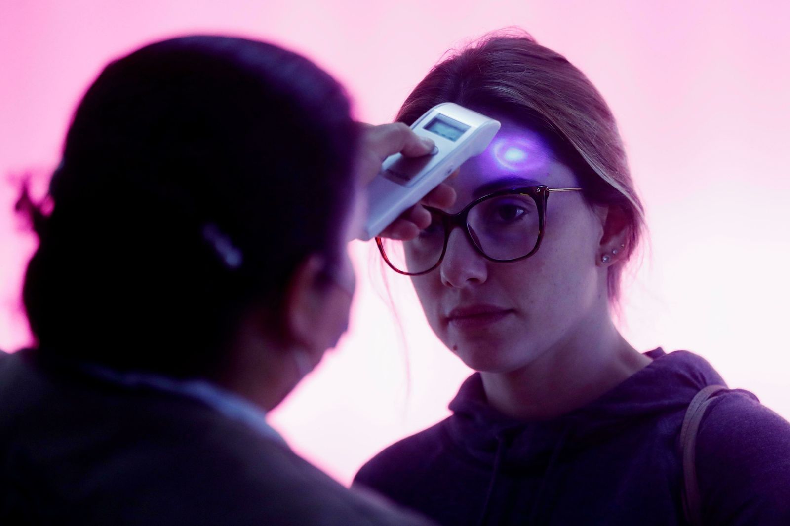 Una sanitaria toma la temperatura a una joven