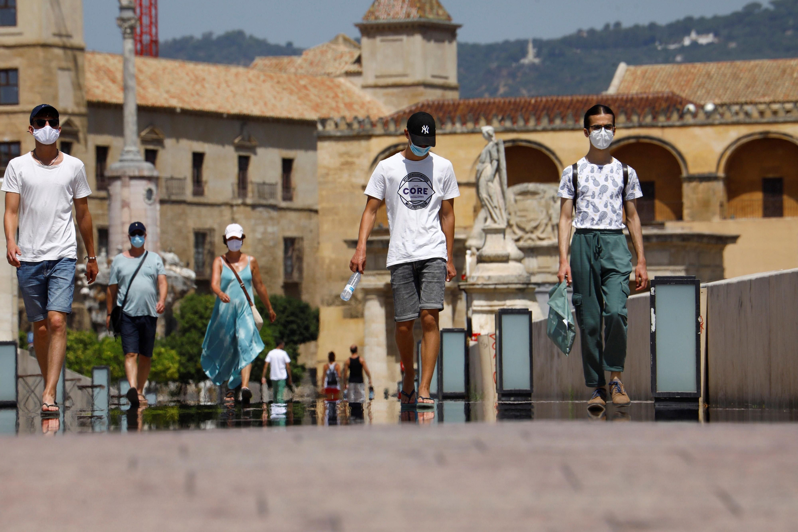 Varias personas caminan por el Puente Romano protegidas con mascarillas.