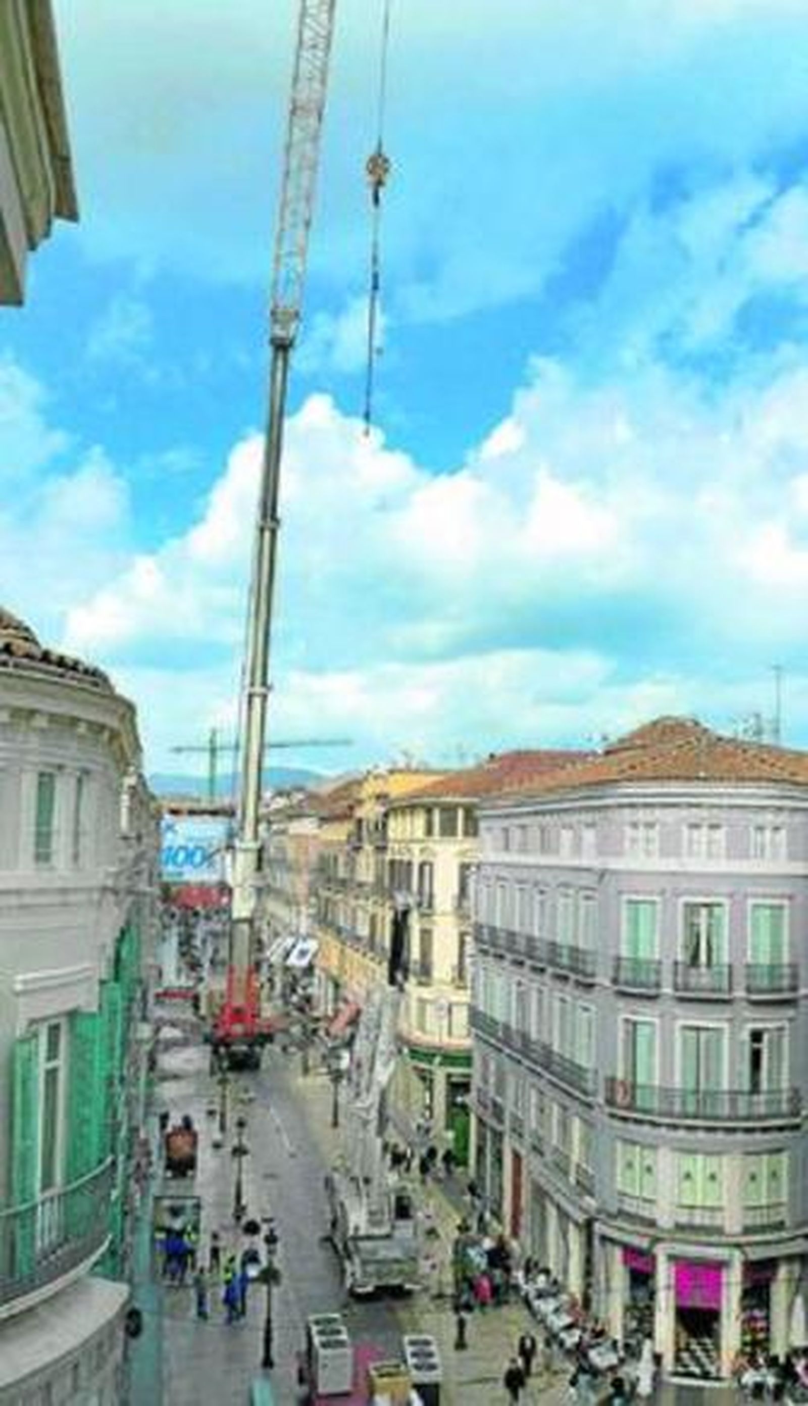 La grúa se dispone a coger, ayer a mediodía, uno de los aparatos de aire acondicionado en la calle Larios.