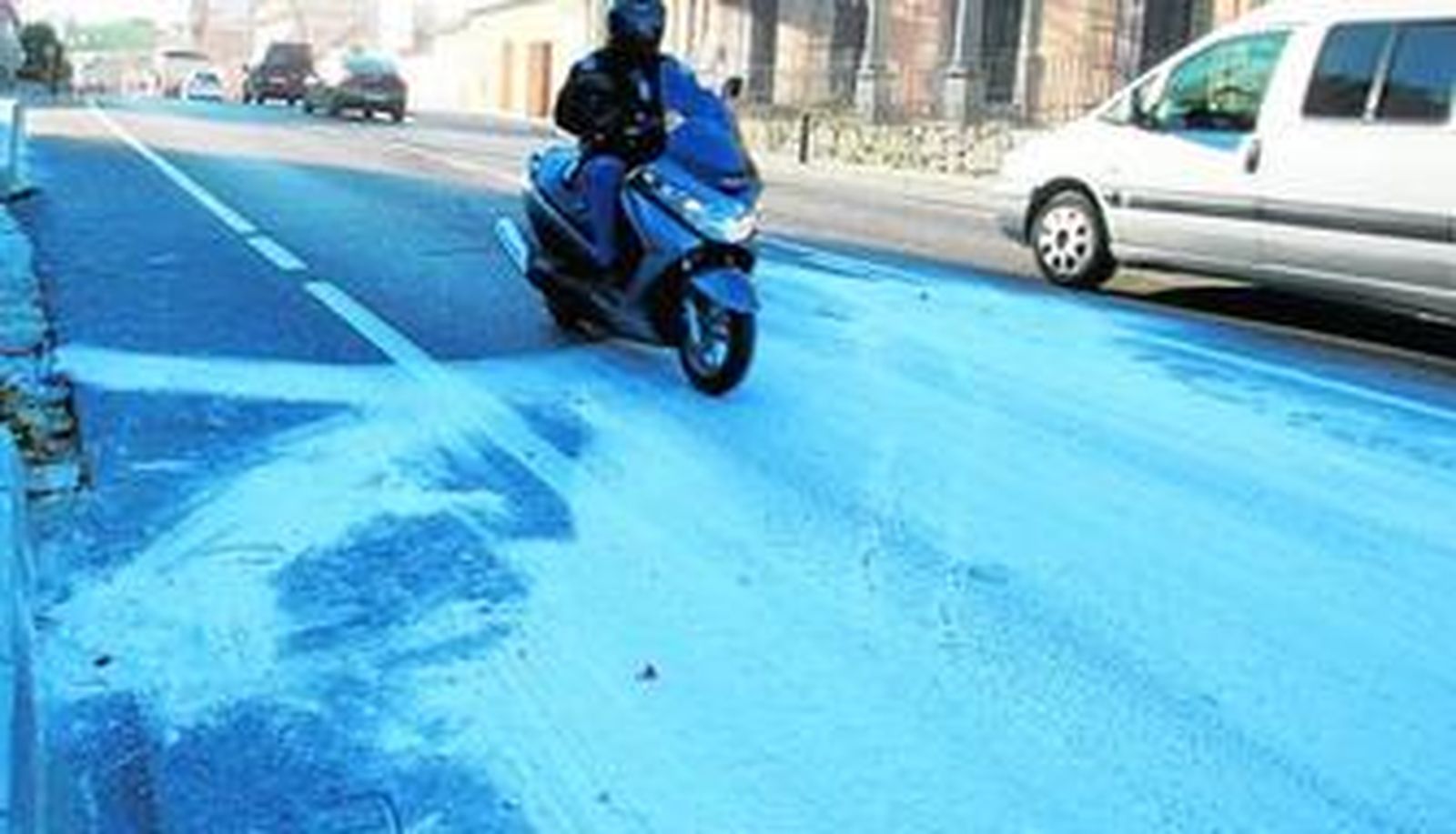 Un motorista circula por la carretera cubierta de arena blanca, tras el accidente, ayer en Campamento.