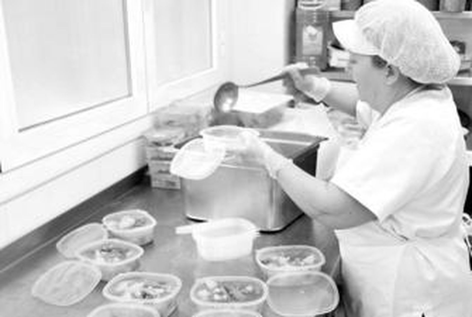 La cocinera sirve en los 'tapers' un plato de papas con carne.