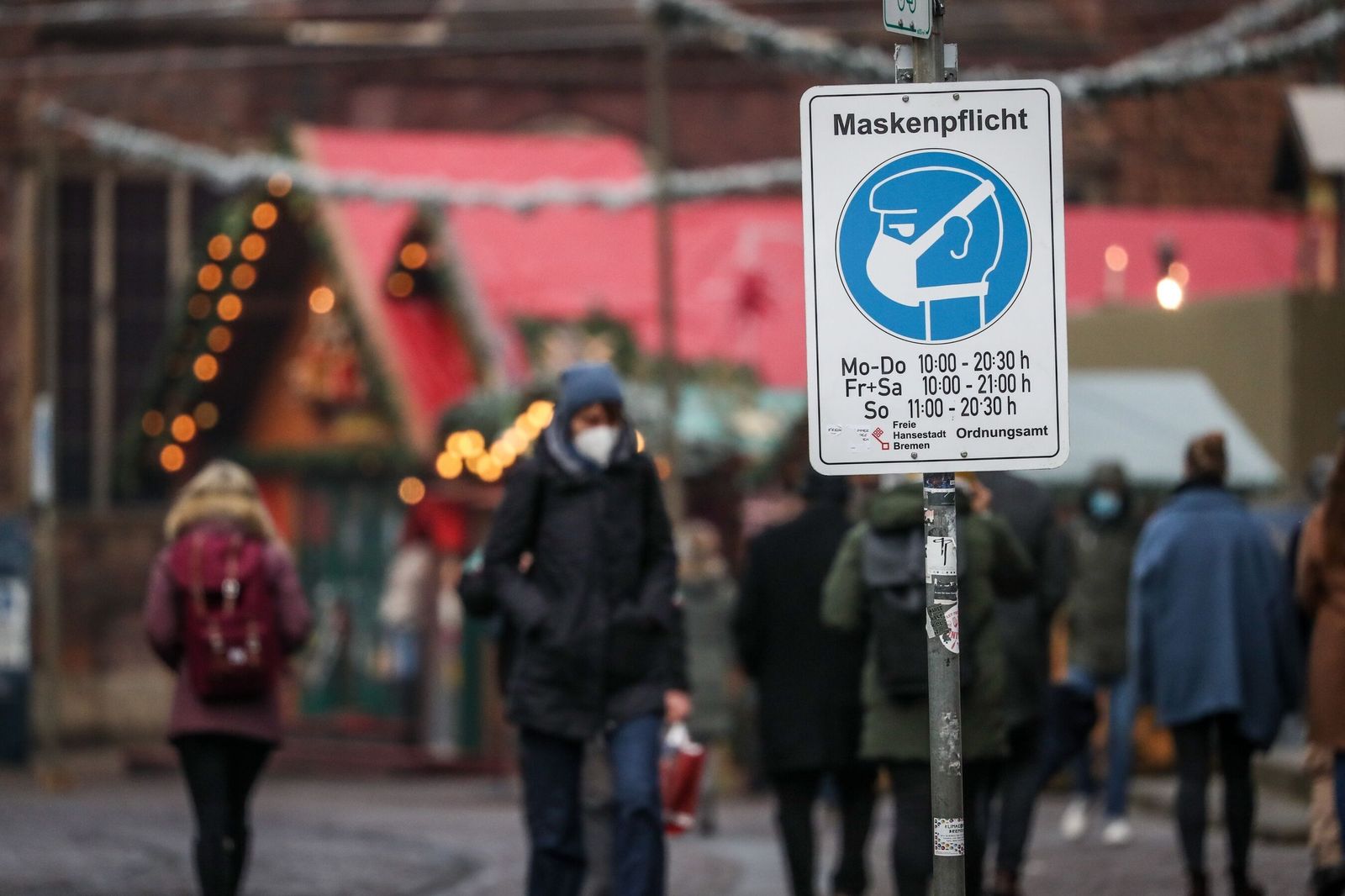Una señal avisa de la obligación de llevar mascarilla en un mercado navideño de Alemania.