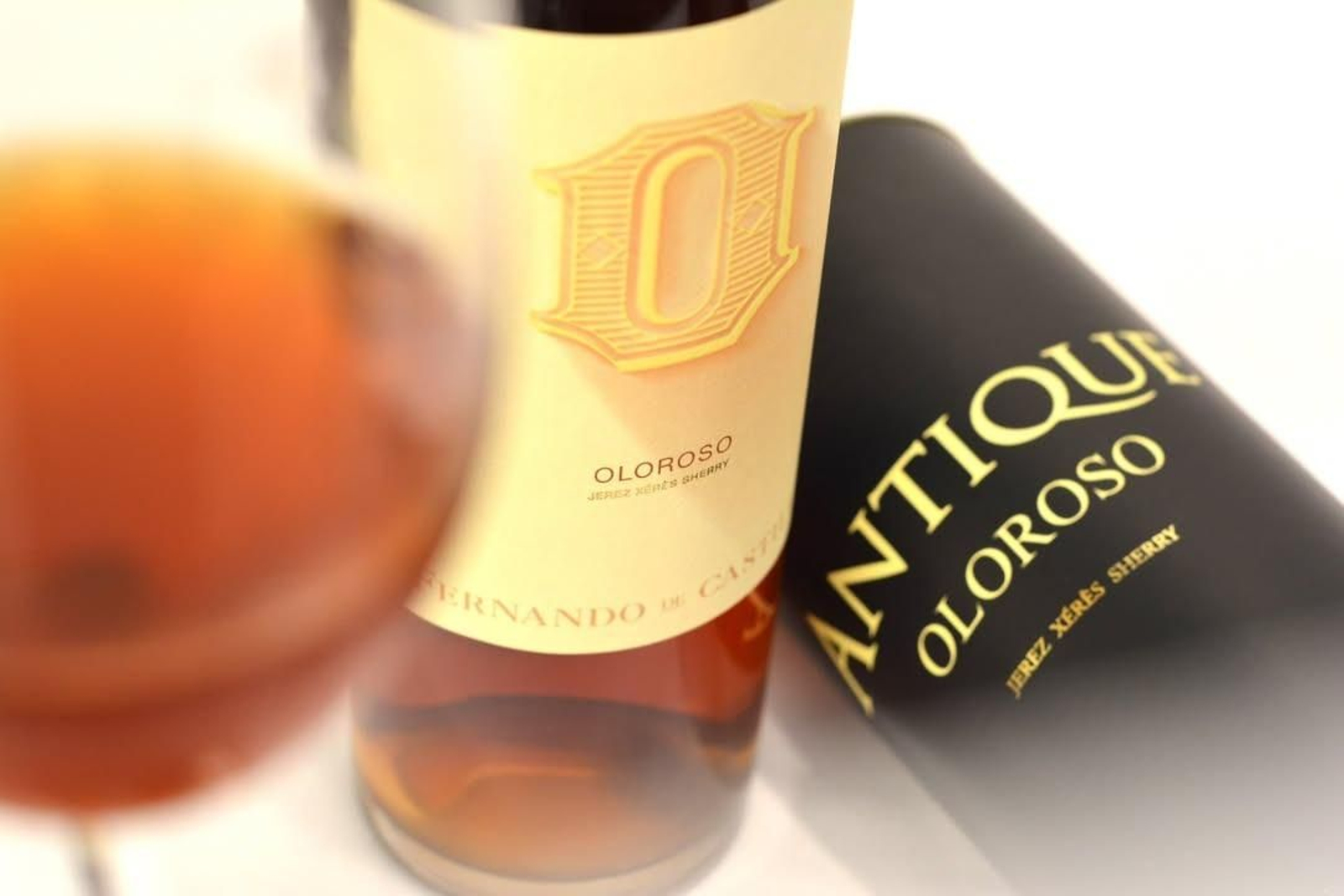 Detalle de la botella y el estuche de Oloroso Antique, junto a una copa del vino premiado por la Guía Gourmets.