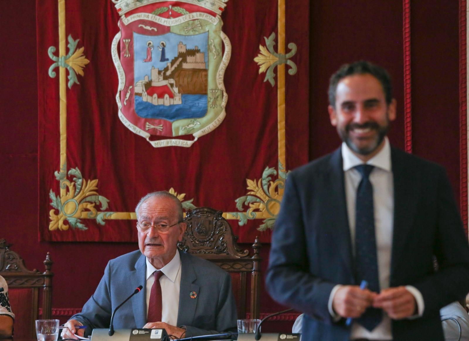Daniel Pérez, en primer plano, sonriente y detrás Francisco de la Torre en el pleno.