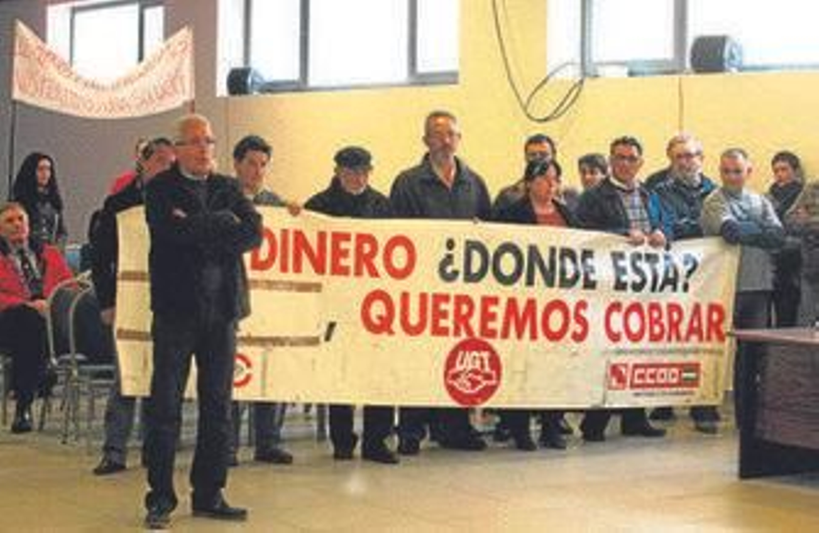 Jesús González Aragón, al frente, durante su intervención en el pleno mientras el resto de delegados sindicales sostiene una pancarta.