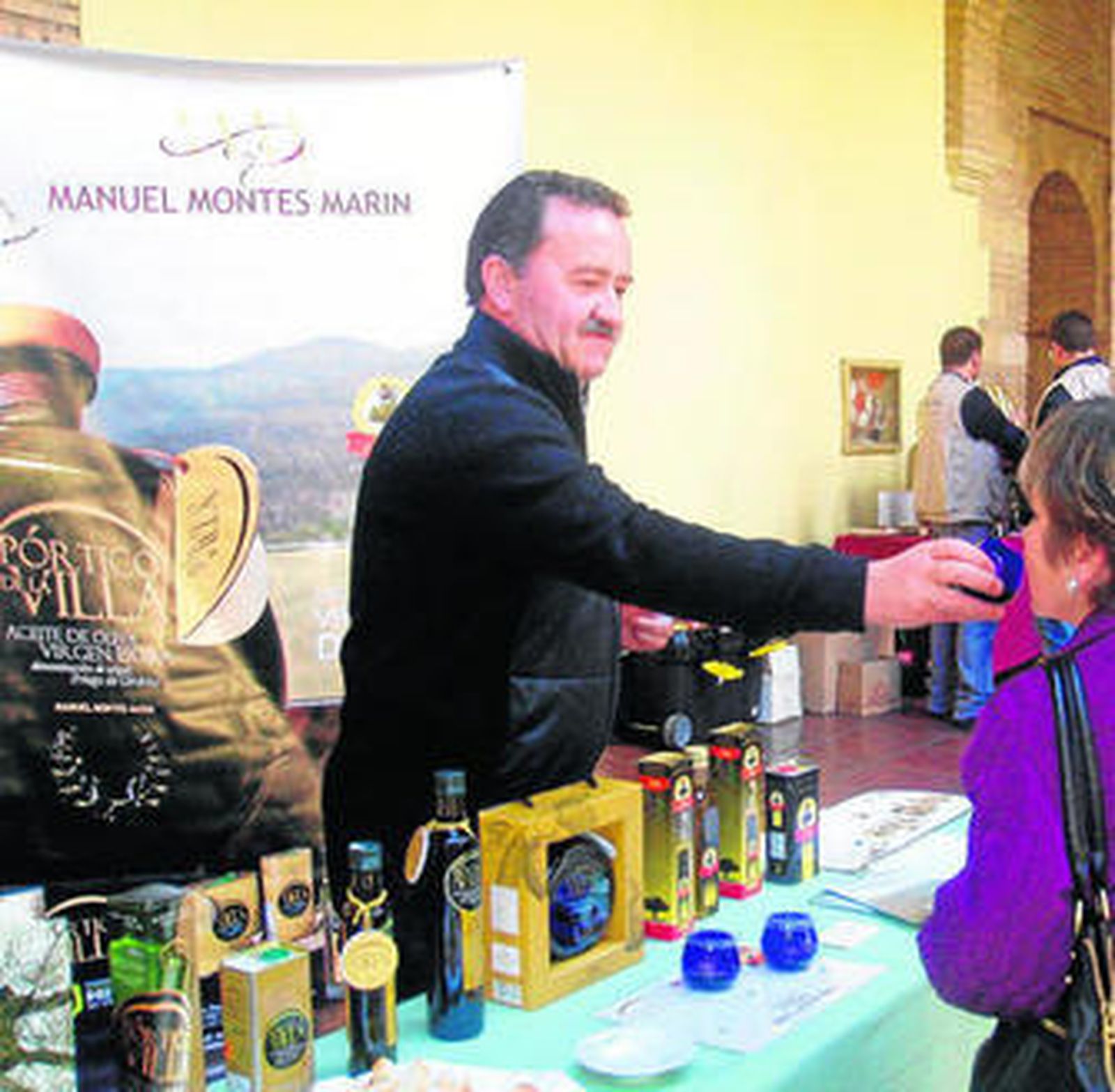 Manuel Montes dando a probar uno de sus aceites, Pórtico de la Villa.