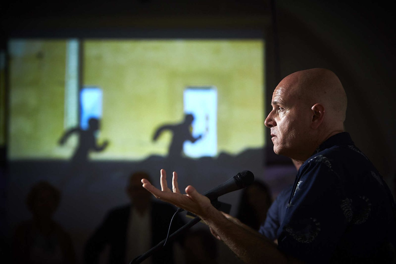 Juan María Rodríguez se dirige a los asistentes a la inauguración de la exposición mientras se proyectan sus fotografías.