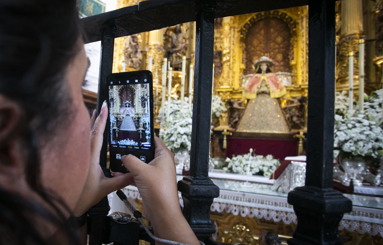 Un devoto realiza una foto con el móvil de la Virgen del Rocío con sus galas de pastora.