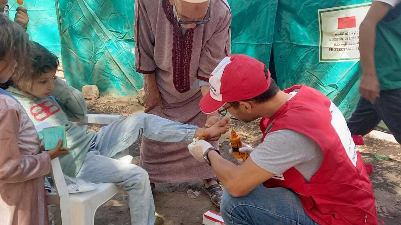 Un voluntario de Cruz Roja cura a una niña herida por el terremoto de Marruecos.