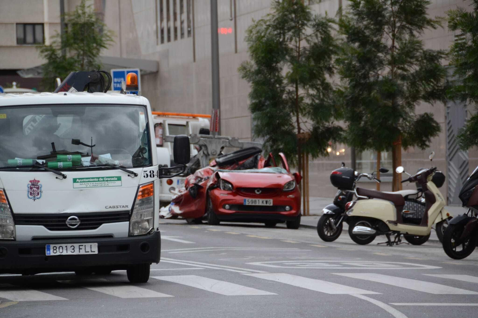 Una mujer resulta ilesa tras caer sobre su vehículo la carga de un camión grúa, en imágenes