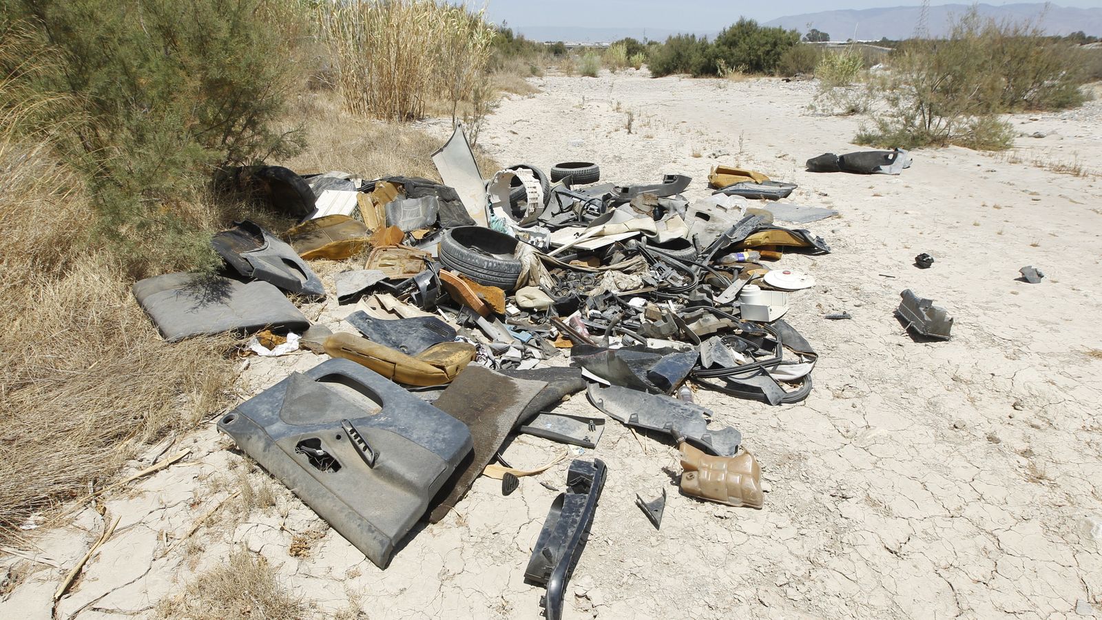 Piezas de un coche desguazado en la desembocadura del río Andarax, a la altura del Club de Natación Almería