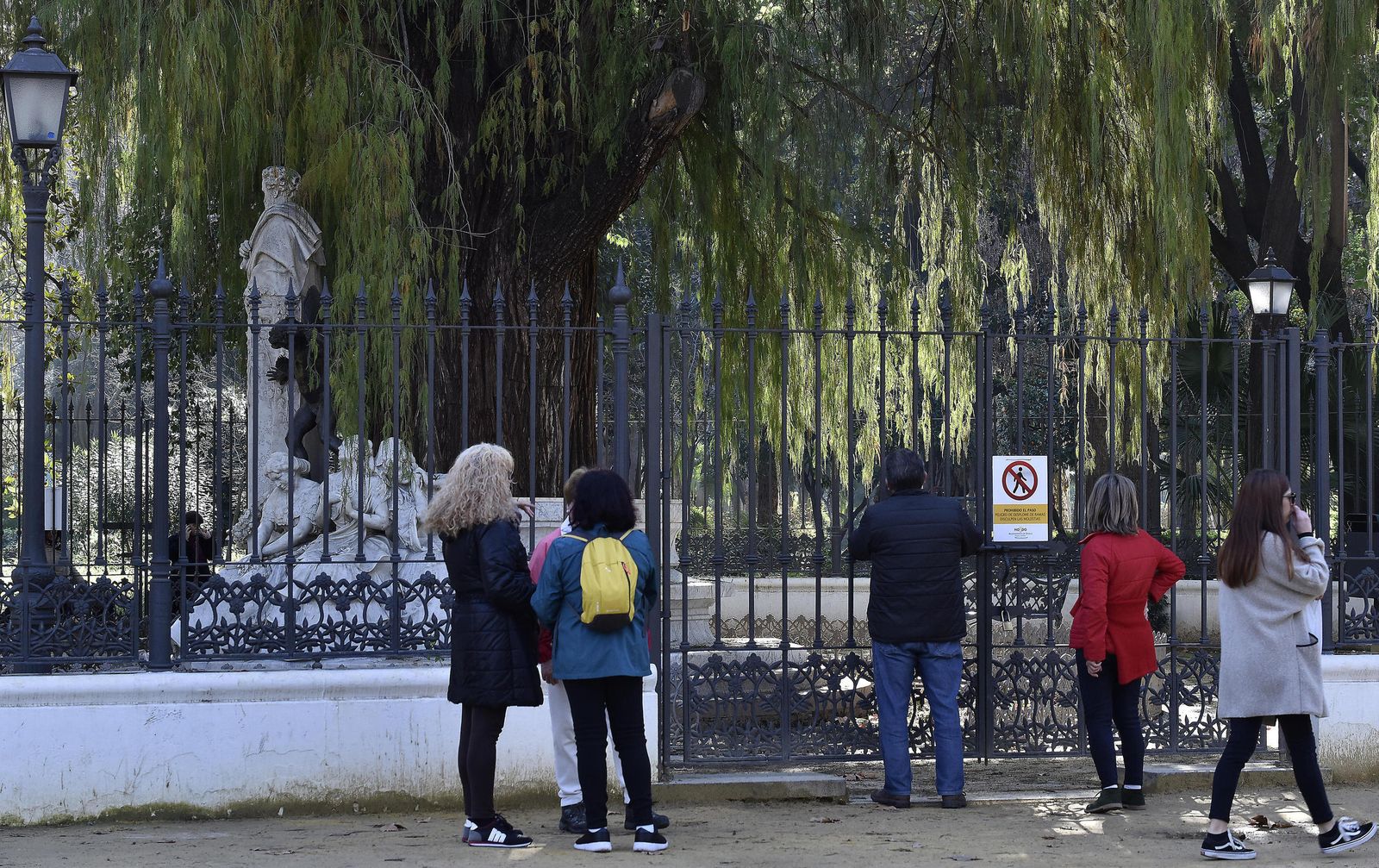 Varios turistas contemplan el monumento a Bécquer tras la verja que lleva varios días cerrada.