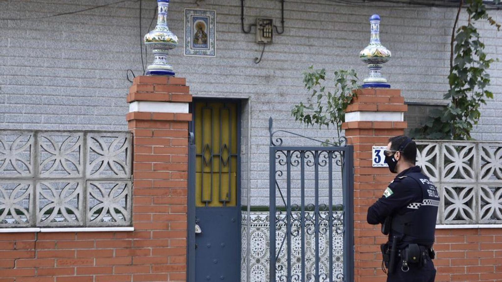 Un policía local de Sevilla, este lunes, ante una casa de Palmete en la que se halló marihuana.