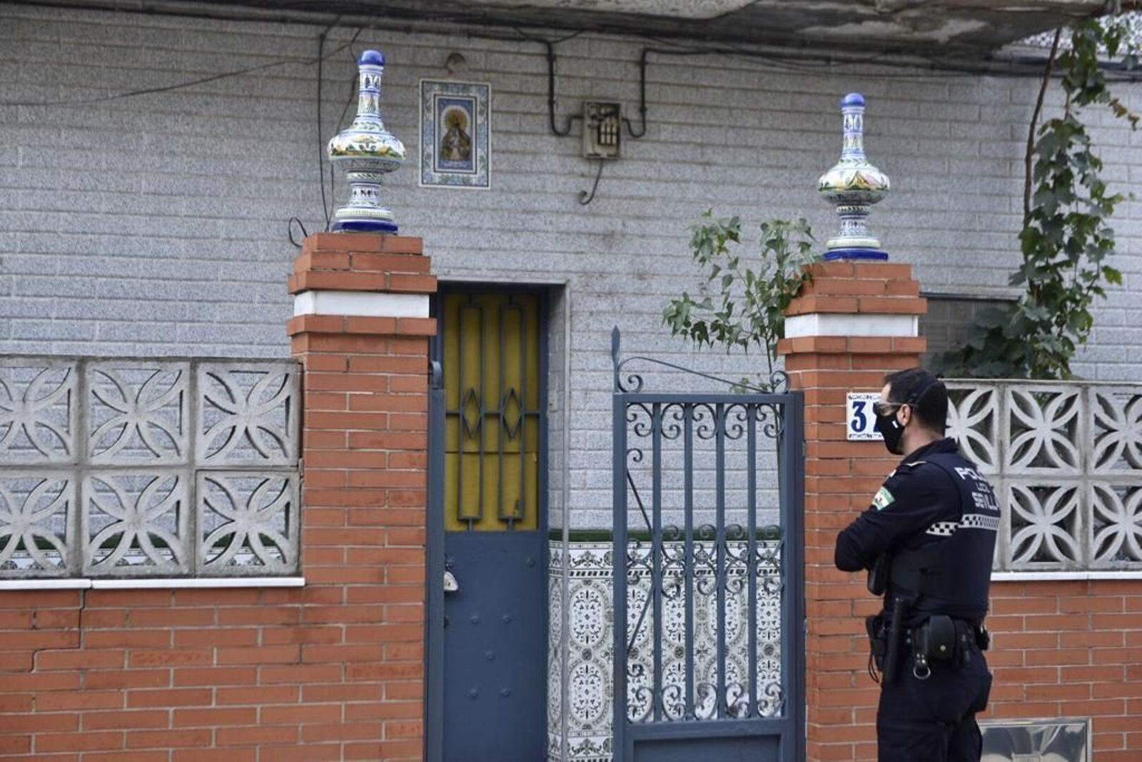 Un policía local de Sevilla, este lunes, ante una casa de Palmete en la que se halló marihuana.