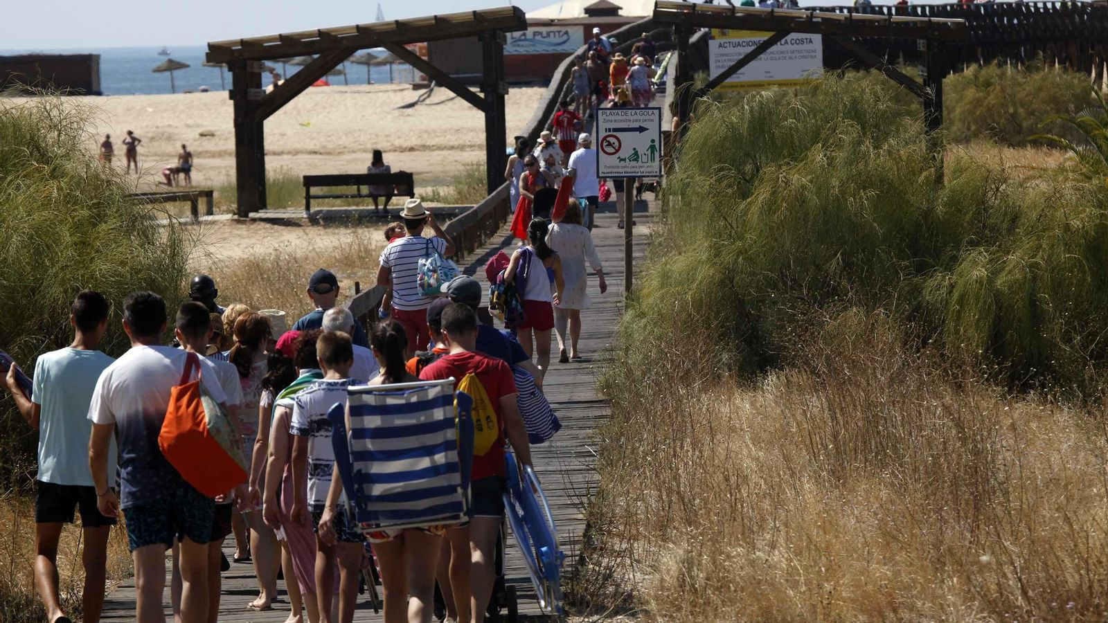 Isleños acceden a la playa a través de la pasarela de madera.