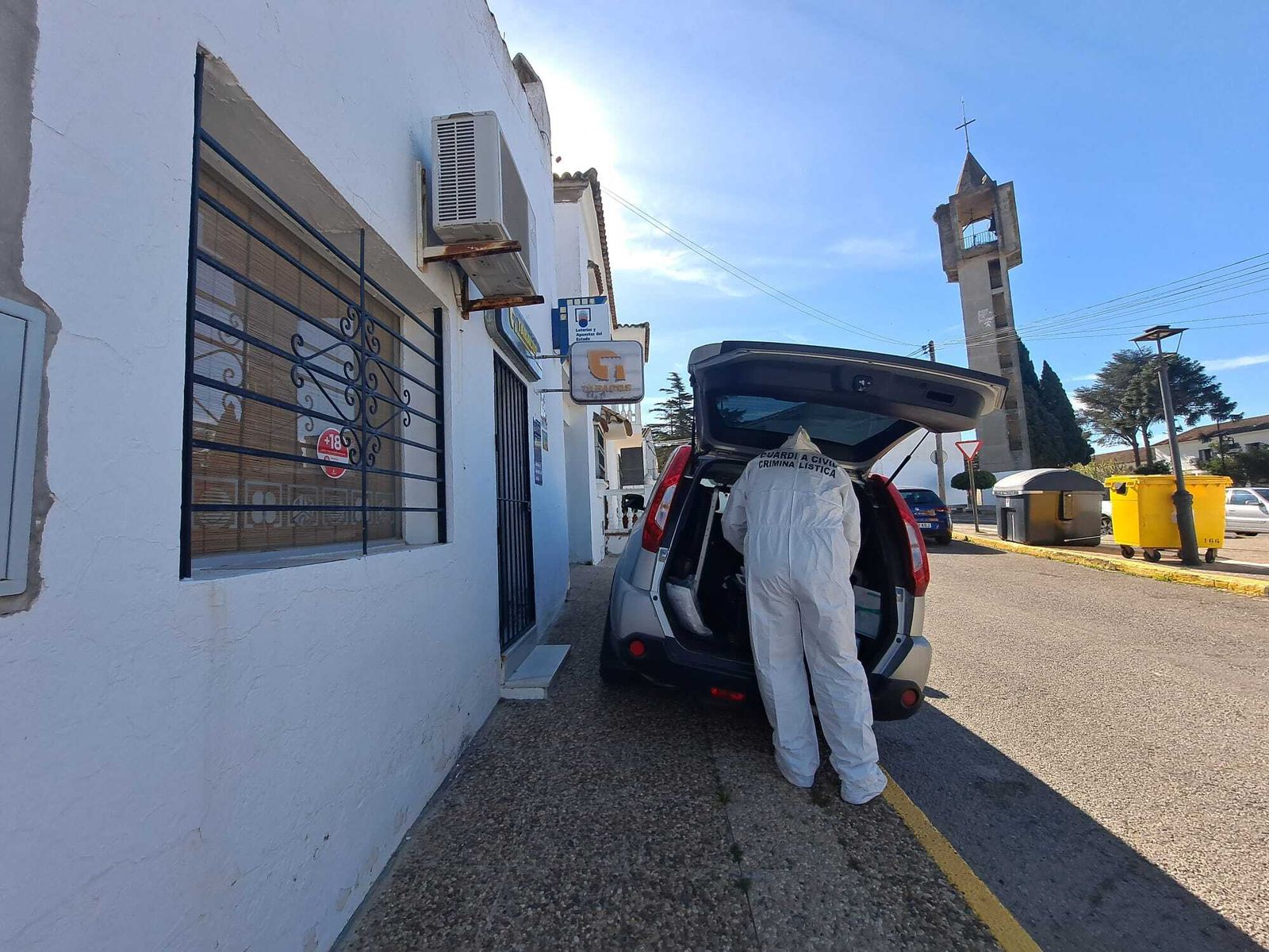 Agente de Criminalística de la Guardia Civil frente al estanco de la mujer herida